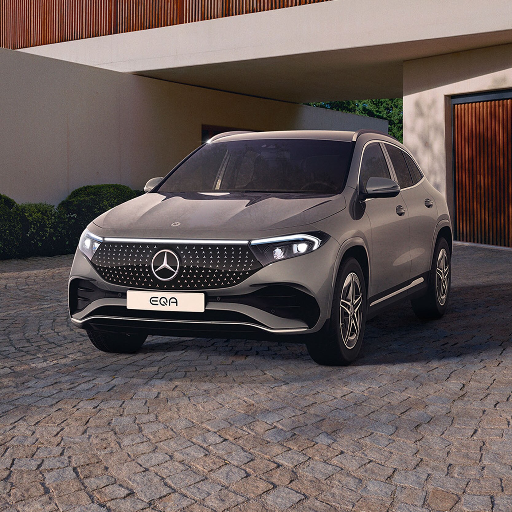 Grå Mercedes-Benz EQA parkeret foran garage ved arkitekttegnet hus