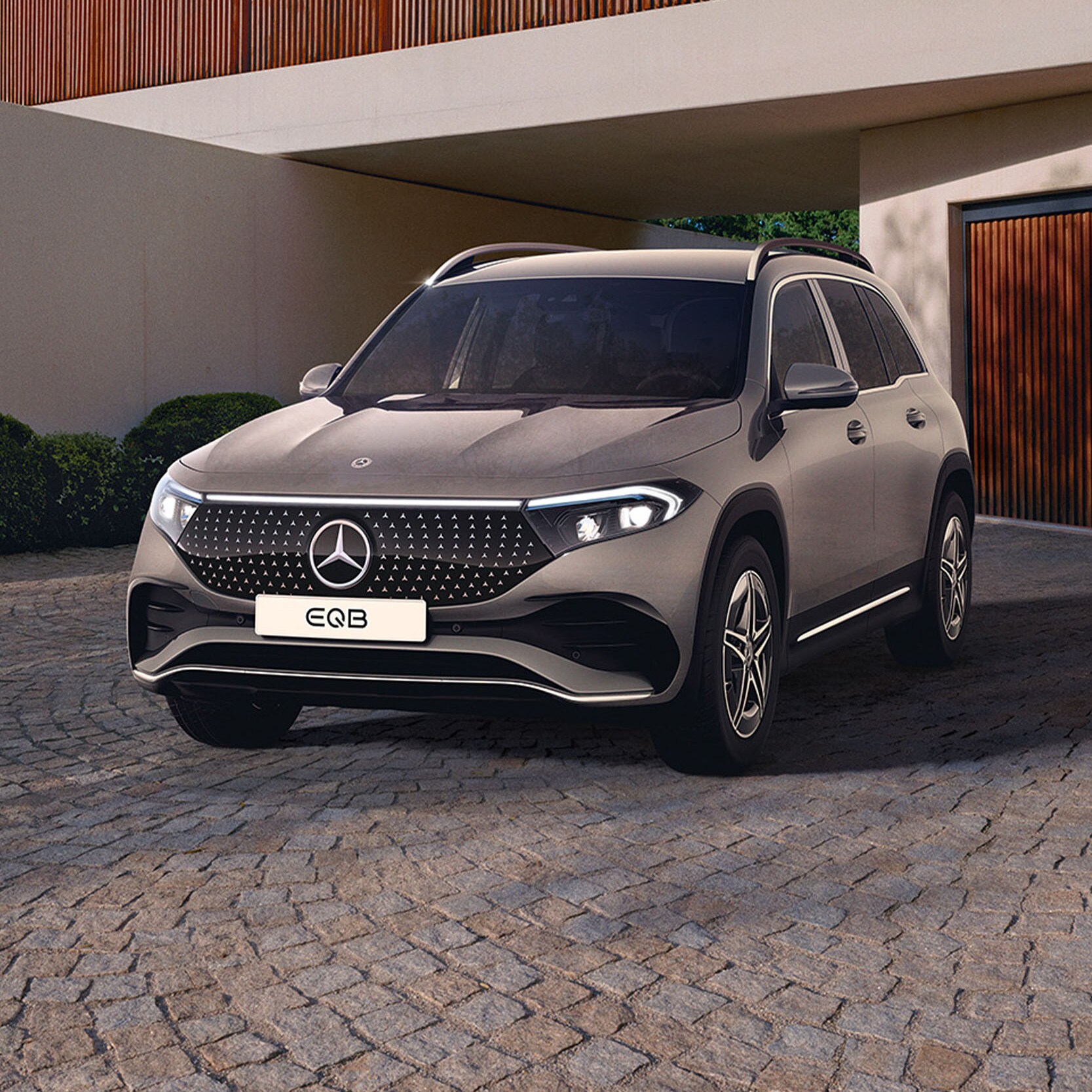 Grå Mercedes-Benz EQB parkeret foran garage ved arkitekttegnet hus