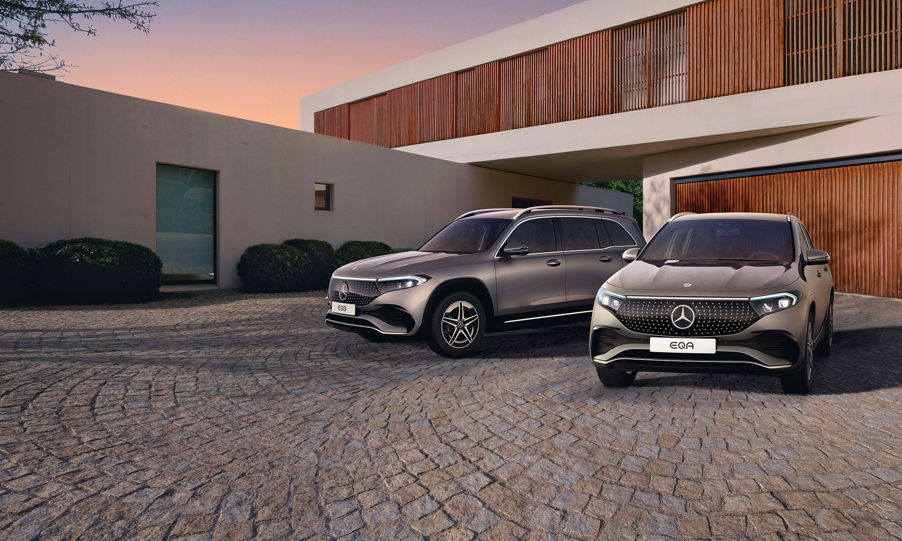 EQA og EQB kampagne | Online Showroom | Mercedes-Benz Mercedes-Benz EQA og EQB i indkørsel foran garage
