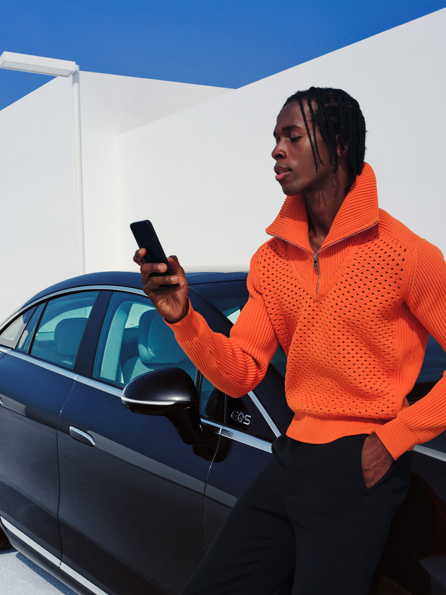 Mand med smartphone læner sig op ad parkeret Mercedes-Benz