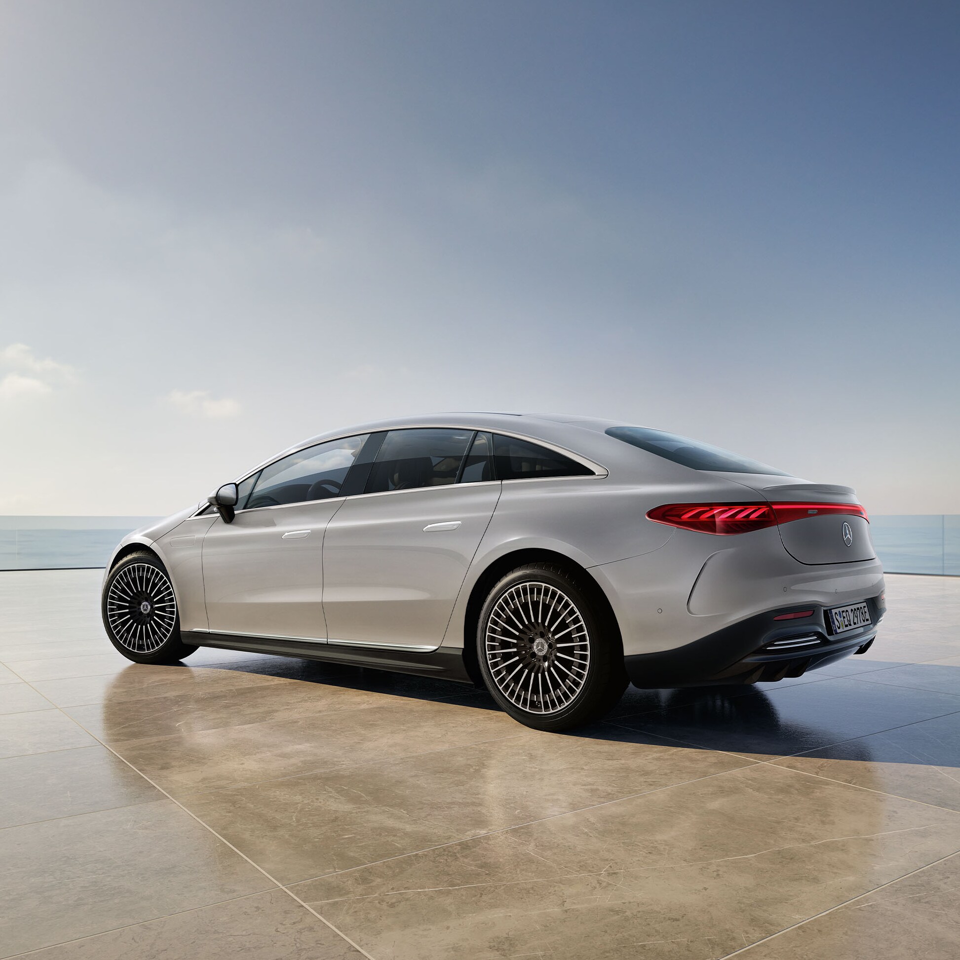 Hvid EQS Sedan fra Mercedes-Benz holder med udkig til vand.