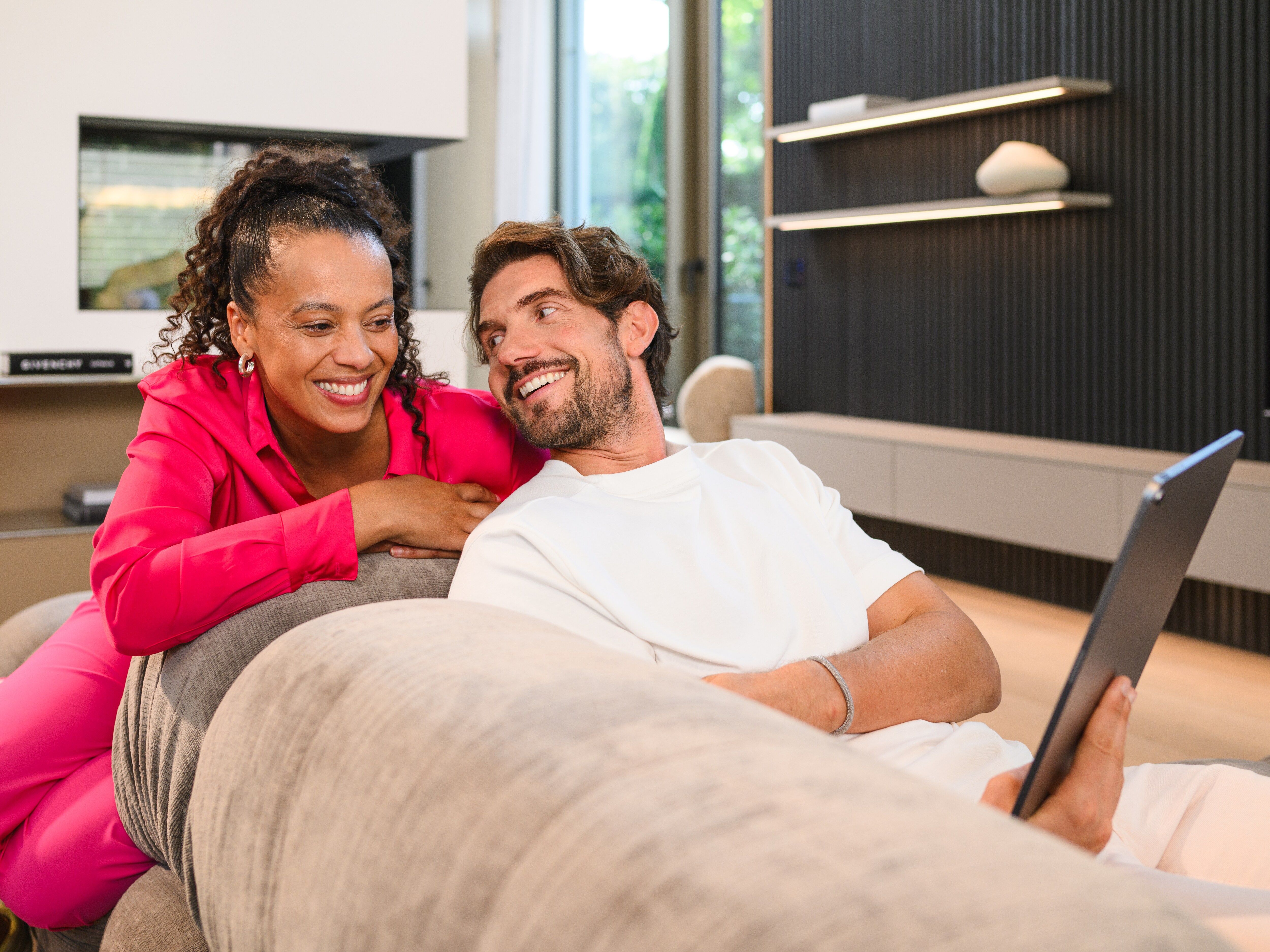 Mand og kvinde kigger på tablet hjemme i deres stue.