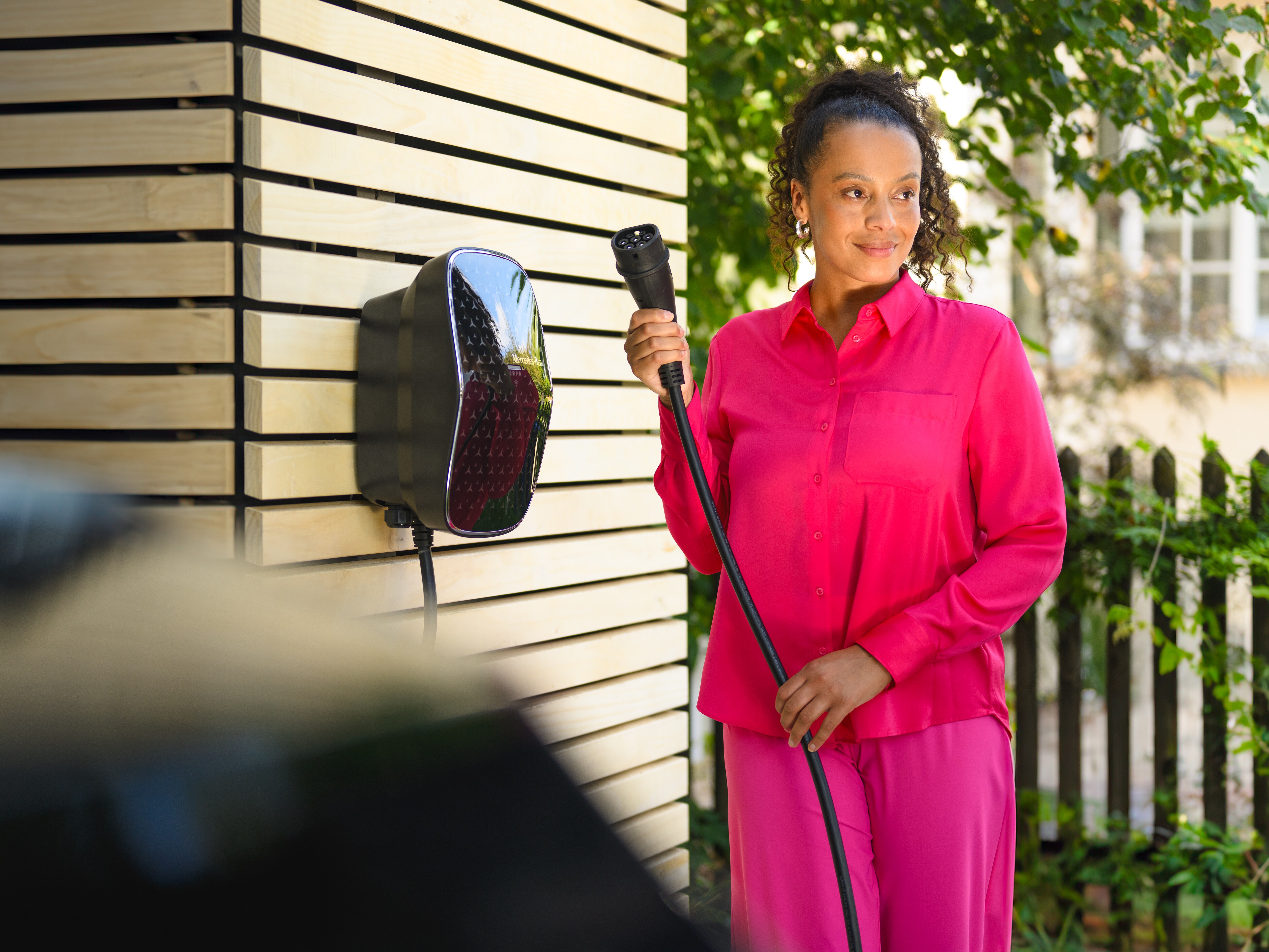 Kvinde henter ladekabel fra wallbox til sin elektriske Mercedes-Benz.