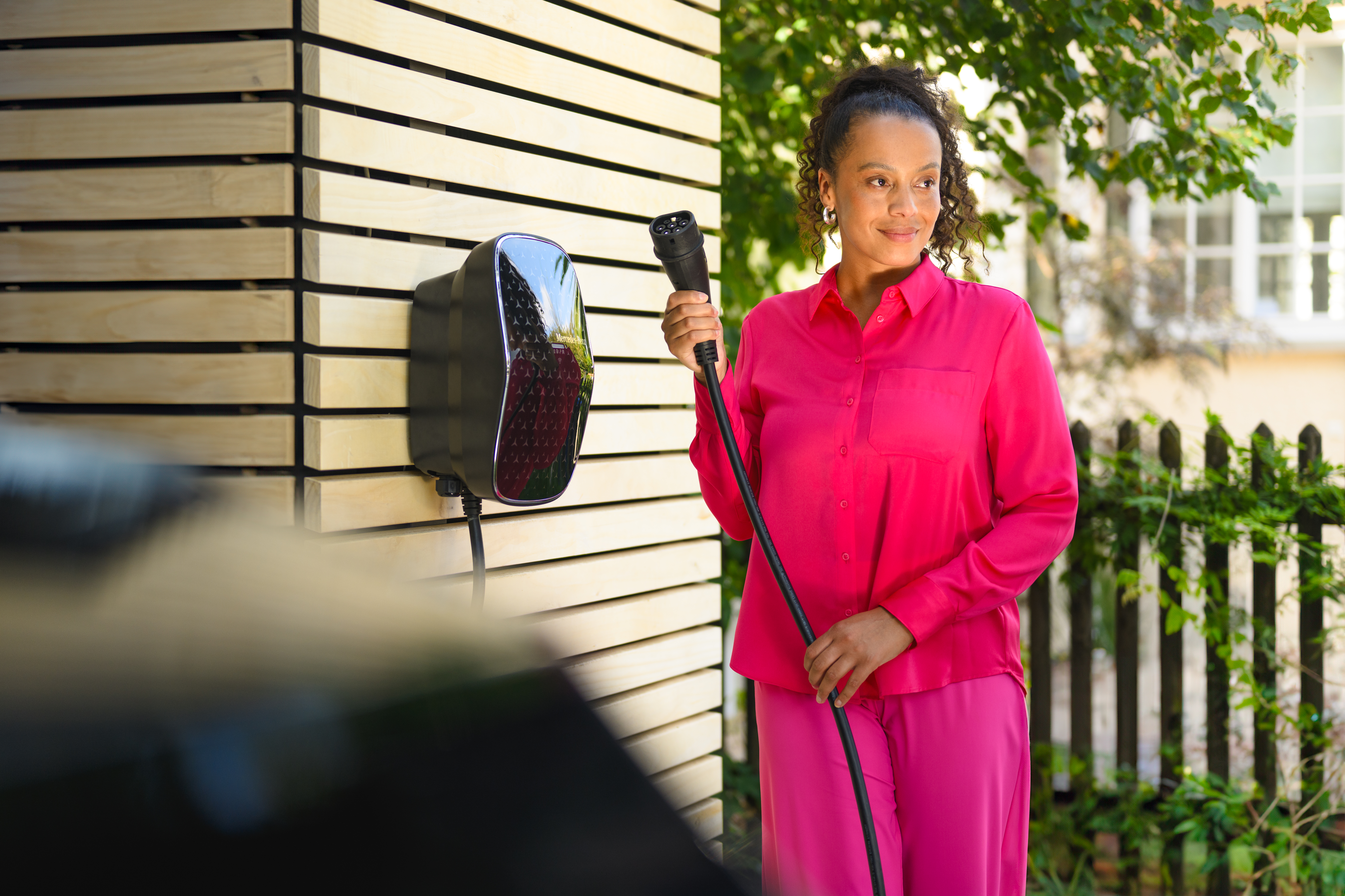 PrivatLeasing | Leasing og finansiering | Mercedes-Benz Kvinde henter ladekabel fra wallbox til sin elektriske Mercedes-Benz.