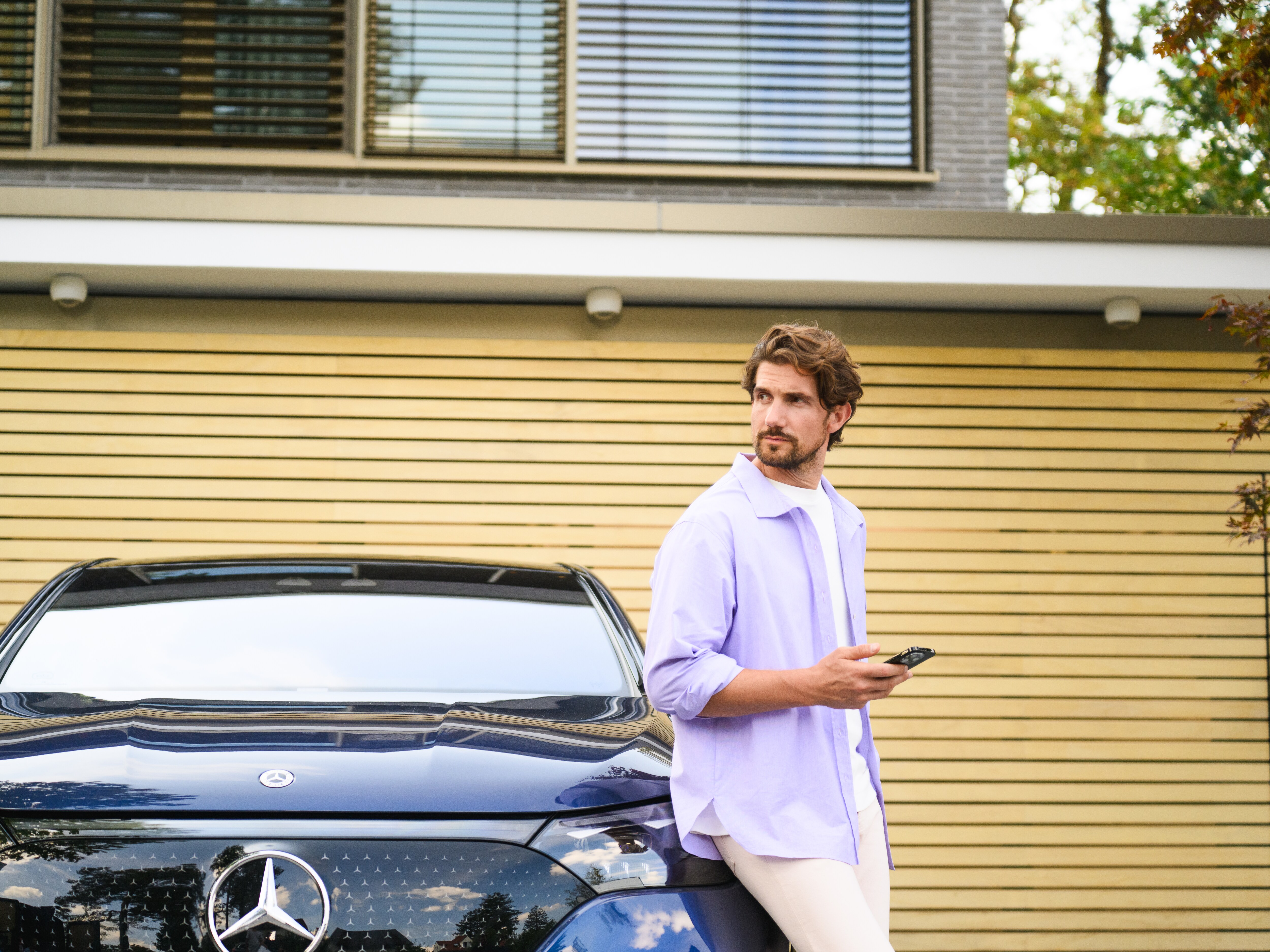 Mand læner sig op ad sin elektriske Mercedes-Benz bil.