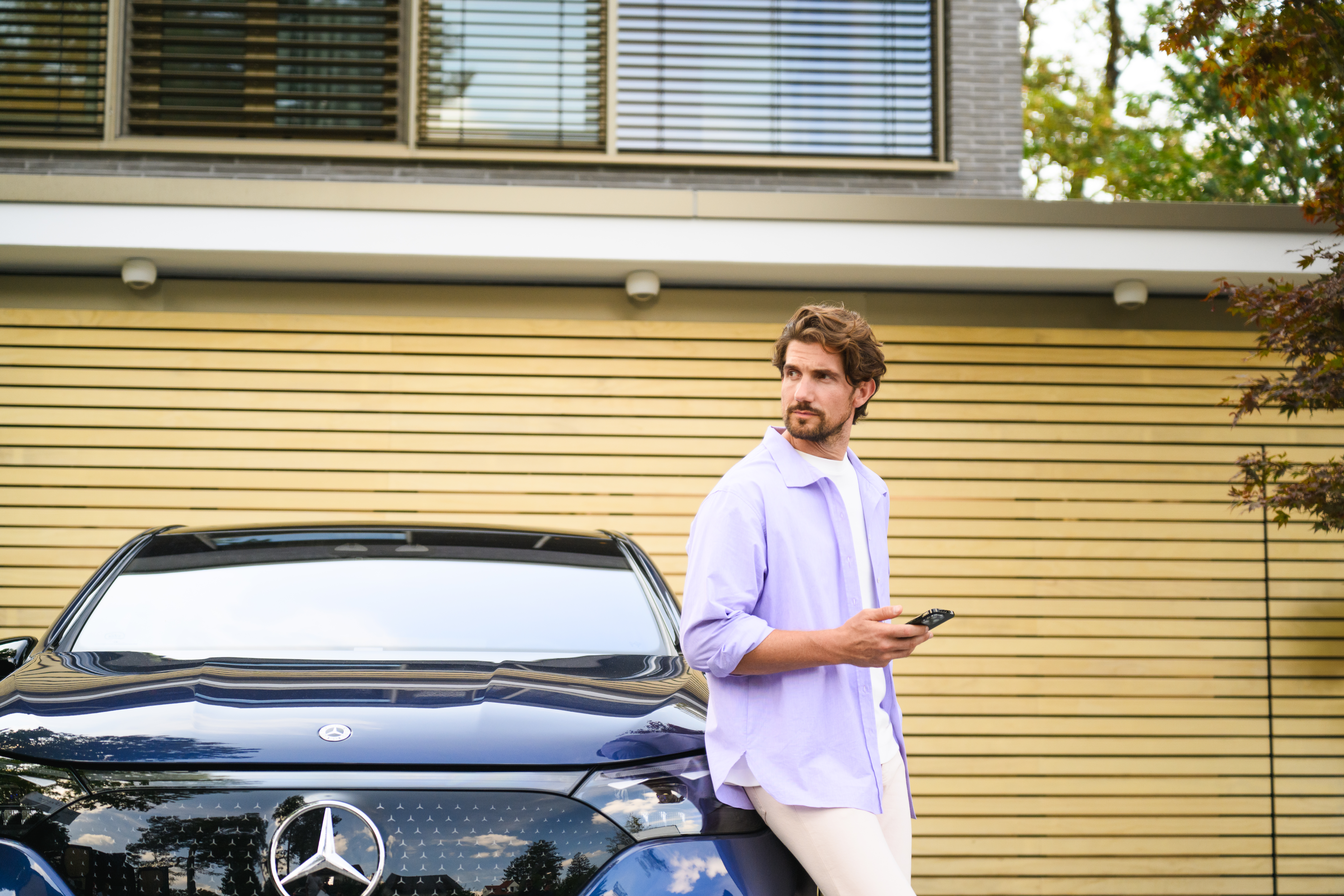 BusinessLeasing | Leasing og finansiering | Mercedes-Benz Mand læner sig op ad sin elektriske Mercedes-Benz bil.