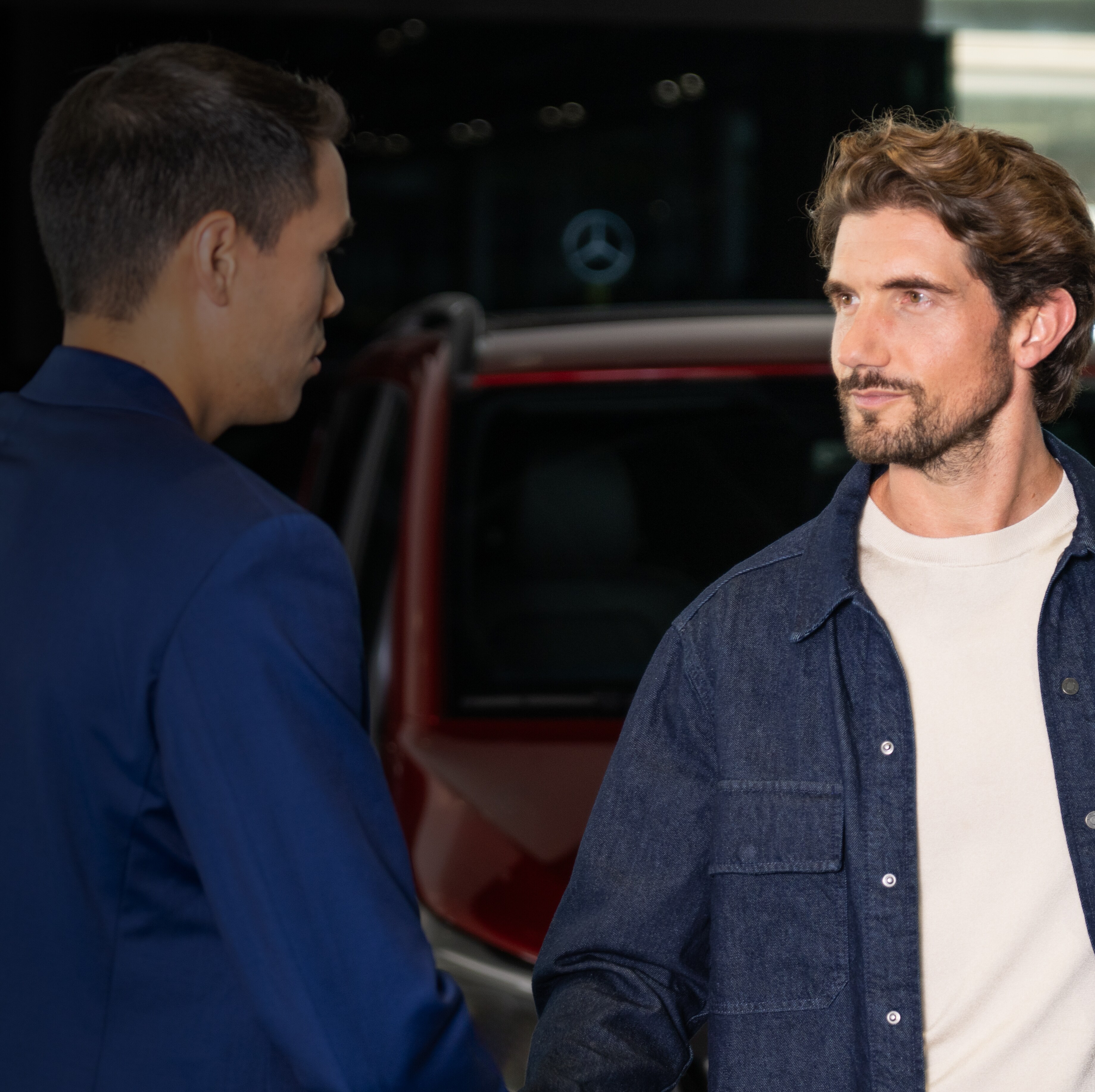 To mænd giver hinanden hånden foran en Mercedes-Benz varebil. 