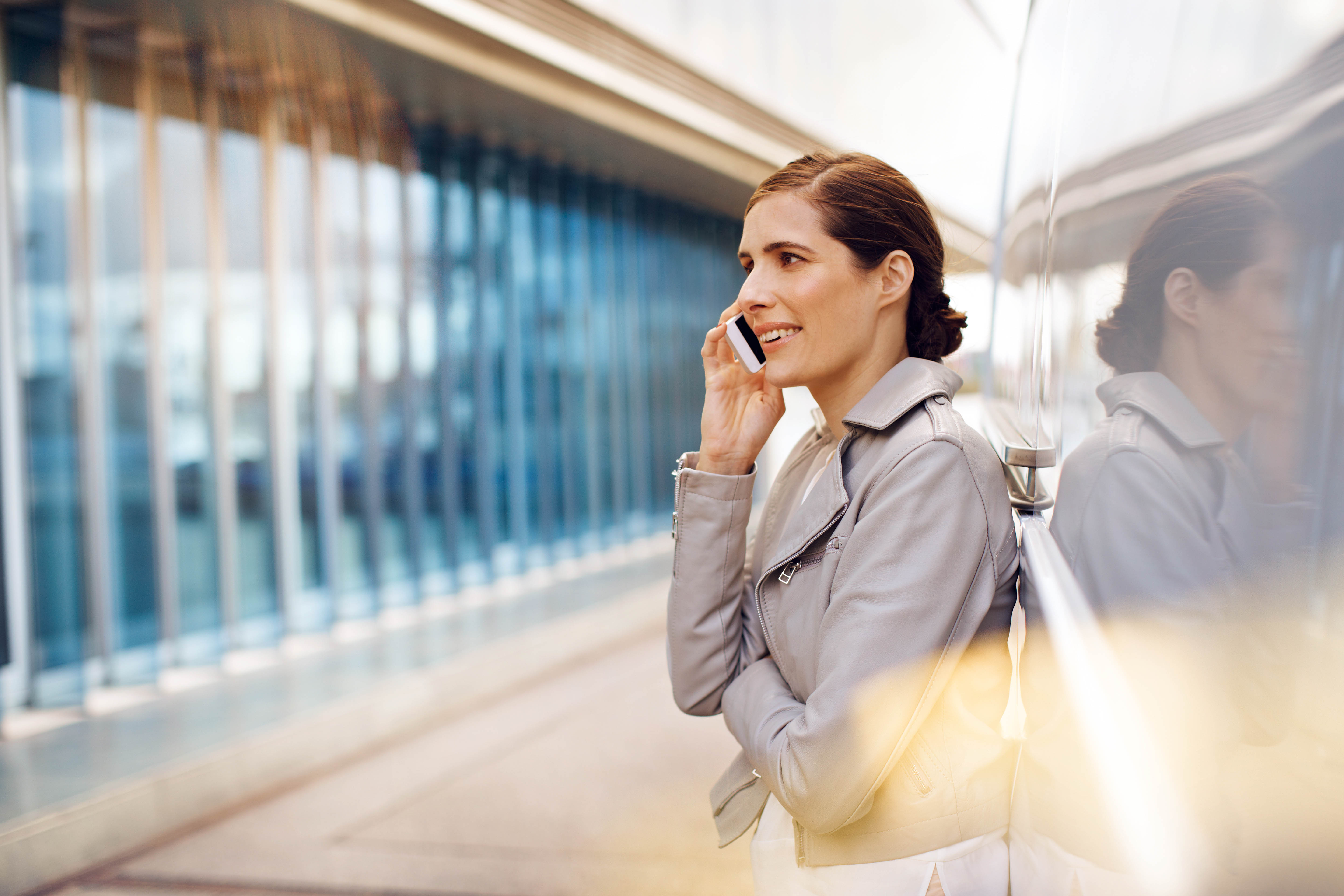 Kundeservice | Mercedes-Benz Vans Kvinde i lys læderjakke står lænet op af Vito Kassevogn og taler i mobiltelefon