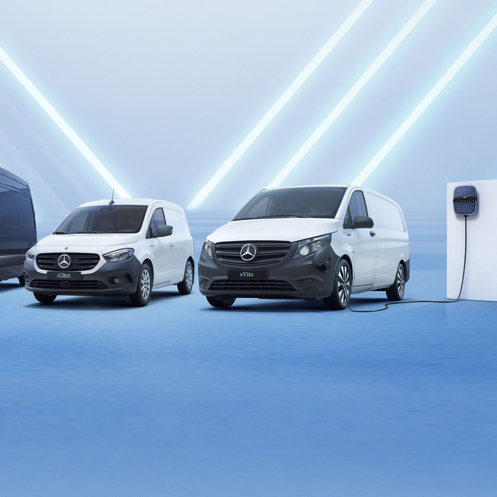 Tre elektriske Mercedes-Benz varebiler på række ved ladestander på væggen til højre