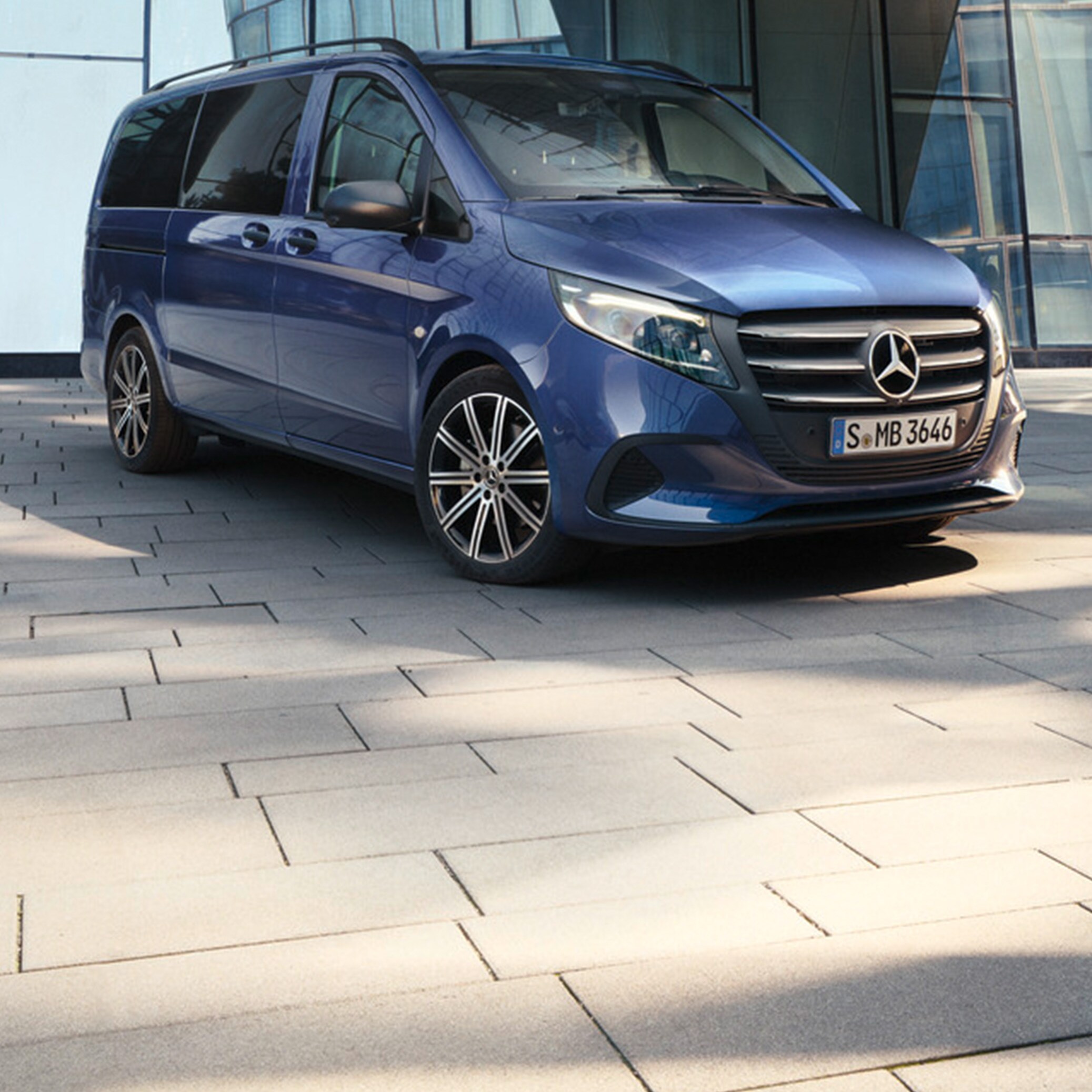 Metallic mørkeblå Vito Tourer parkeret ved bygning med glasfacade