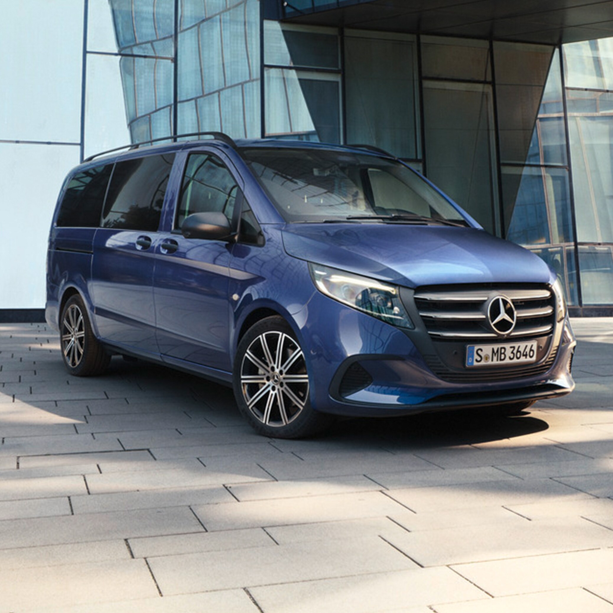 Metallic mørkeblå Vito Tourer parkeret ved bygning med glasfacade