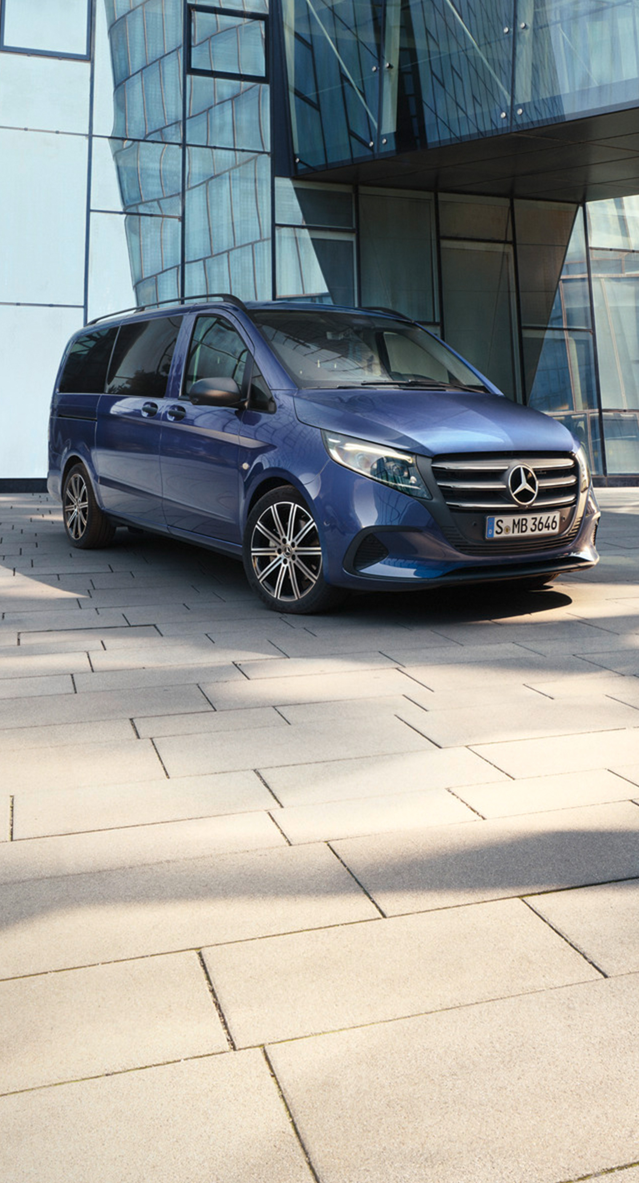 Metallic mørkeblå Vito Tourer parkeret ved bygning med glasfacade