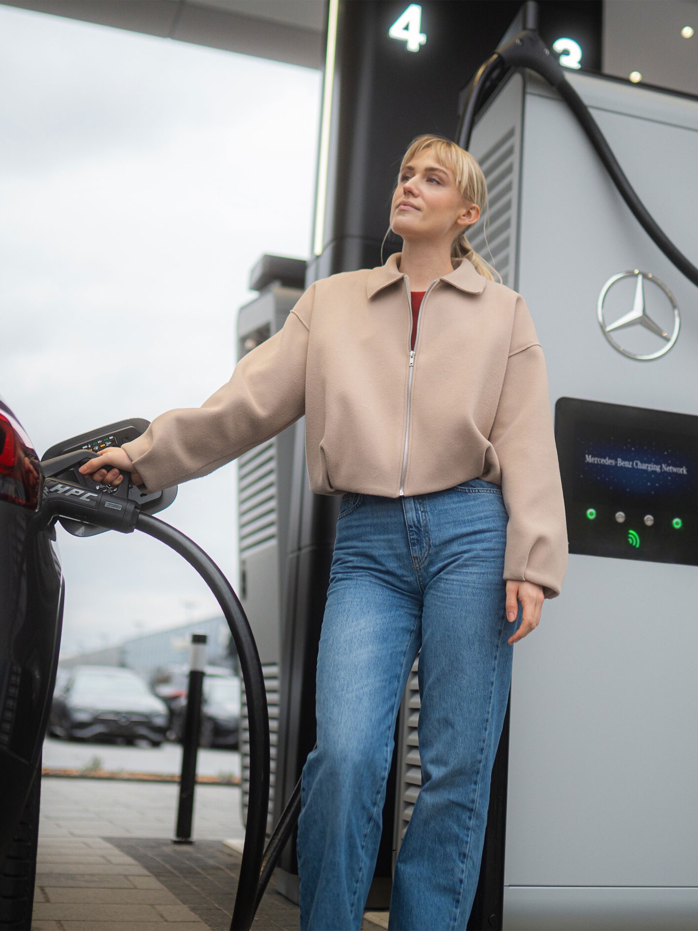 Kvinde oplader sin Mercedes-Benz elbil ved en ladestander via MB.CHARGE Public