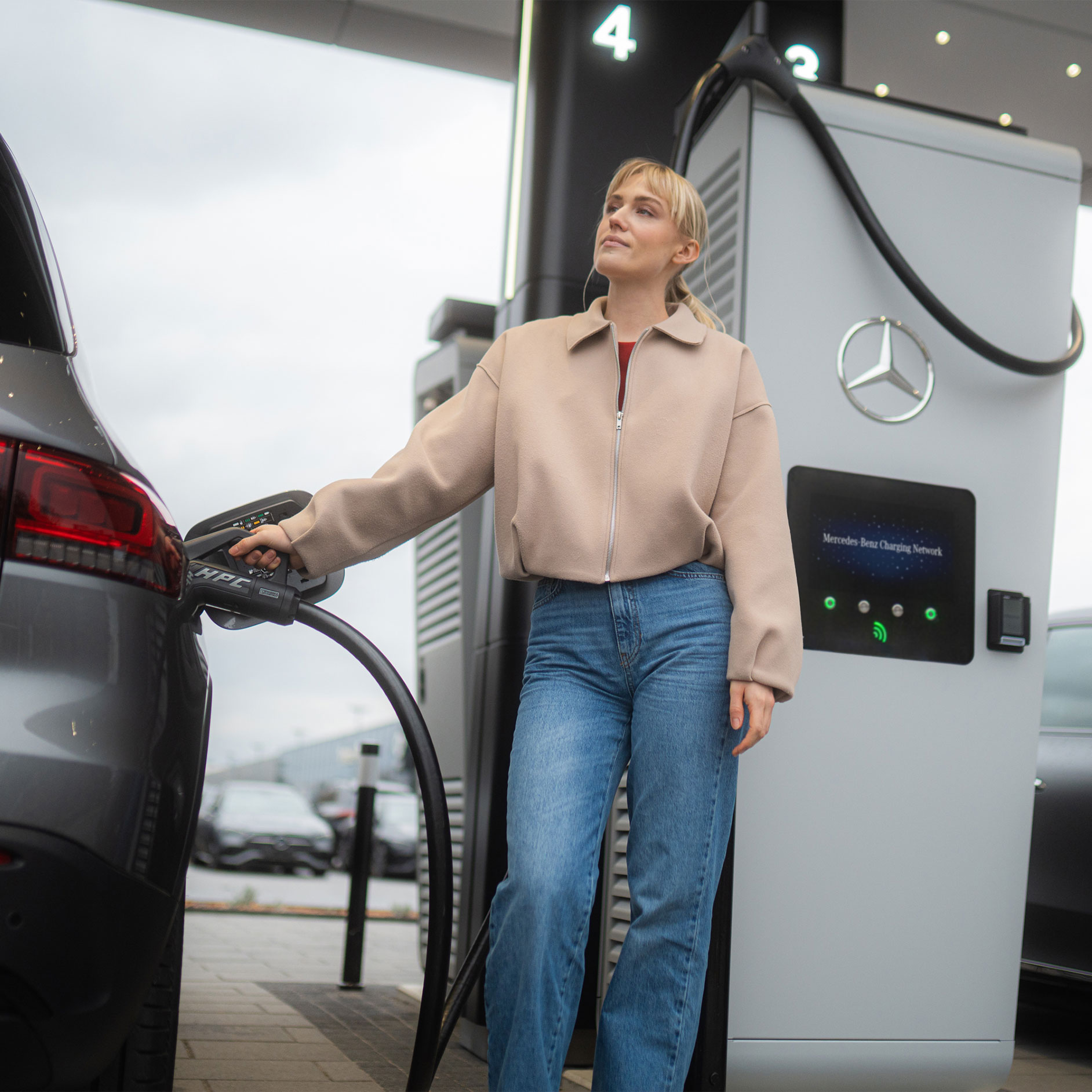 MB.CHARGE Public | Wallbox og opladningsudstyr | Mercedes-Benz Kvinde oplader sin Mercedes-Benz elbil ved en ladestander via MB.CHARGE Public
