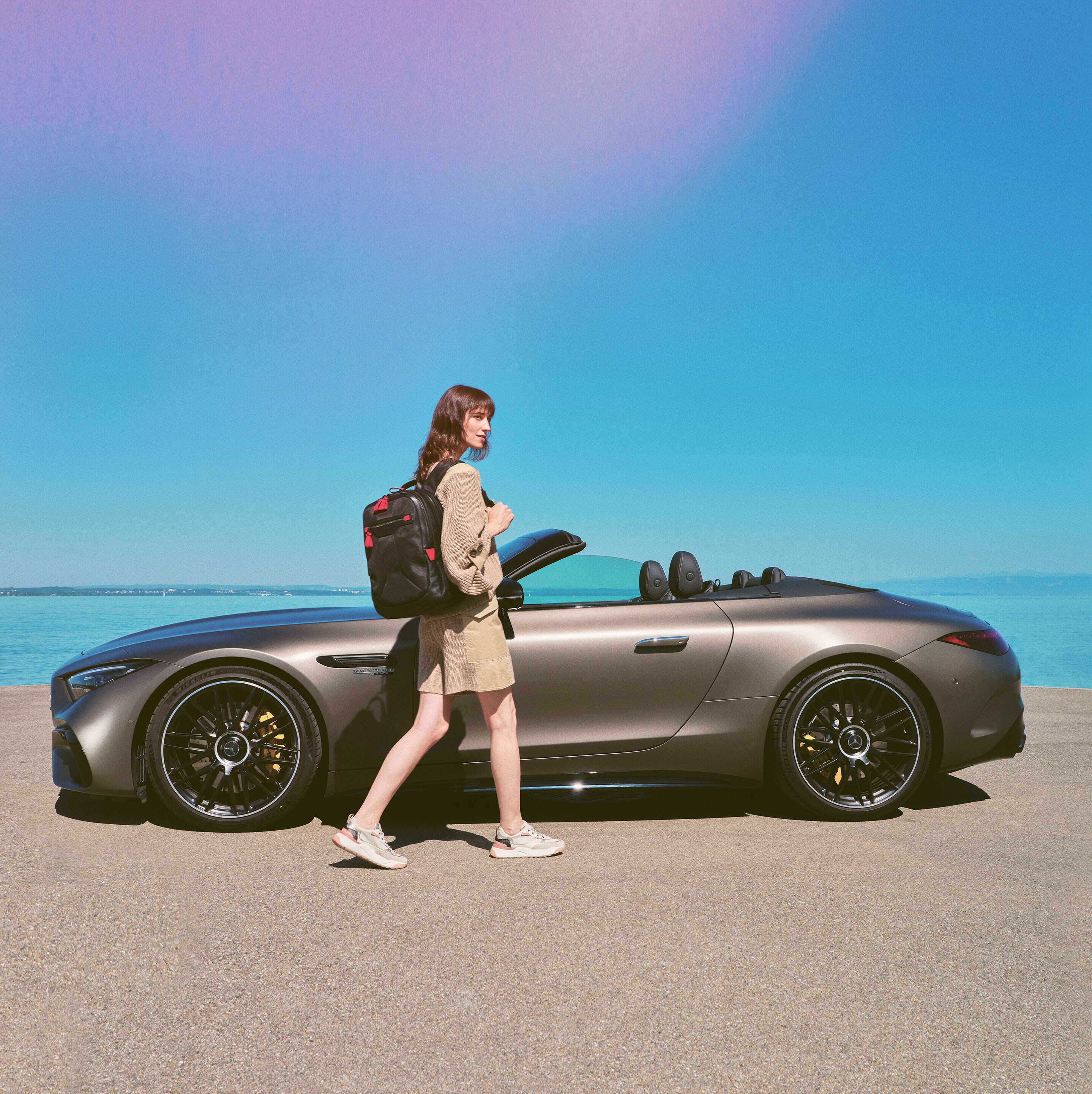 Kvinde går mod Mercedes-Benz cabriolet parkeret ved strand
