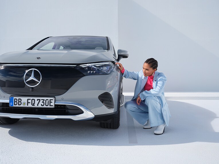 Kvinde inspicerer bule på fronten af sin Mercedes-Benz personbil
