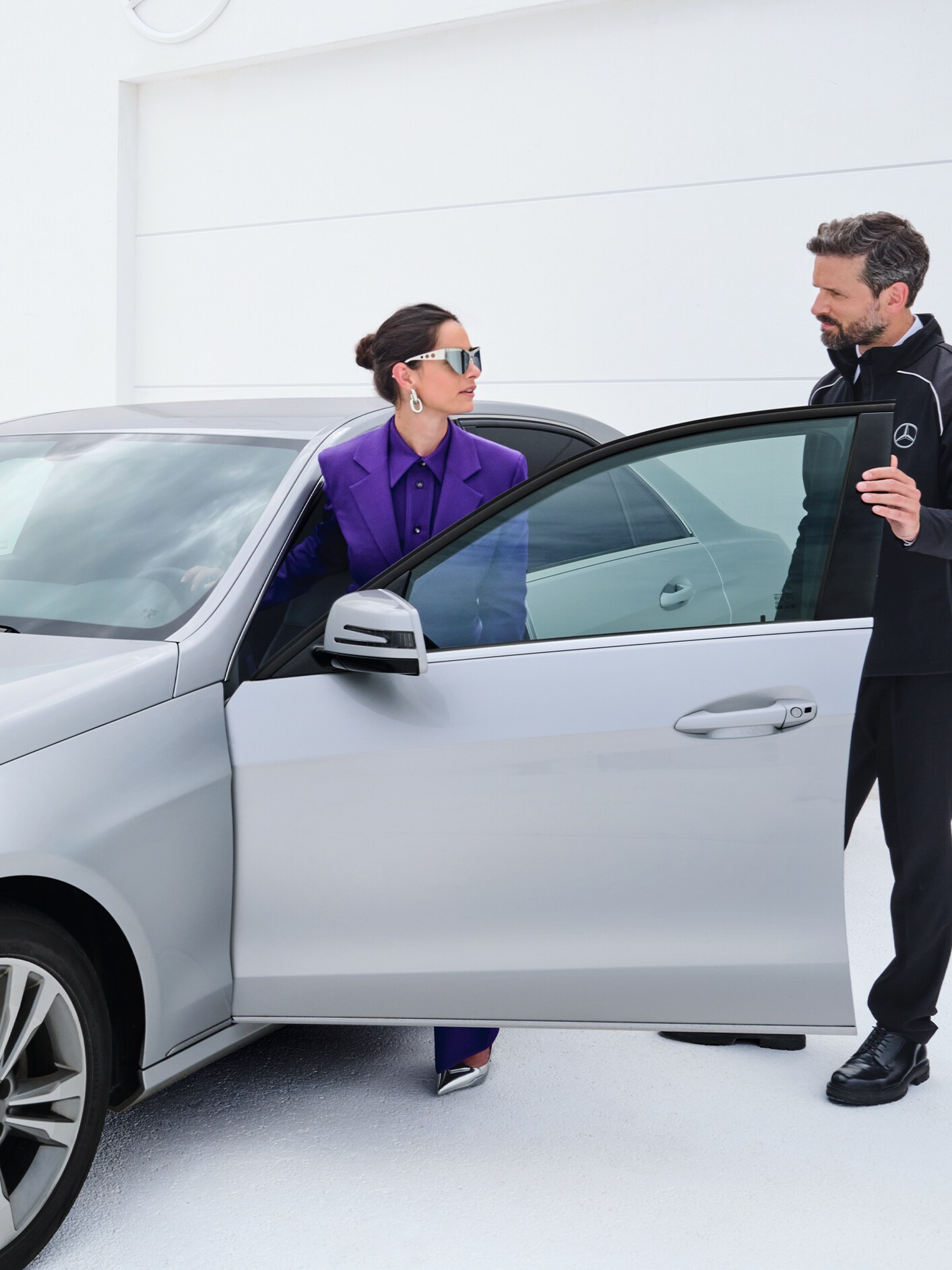 Kvinde stiger ind i sin bil mens hun taler med Mercedes-Benz servicemedarbejder