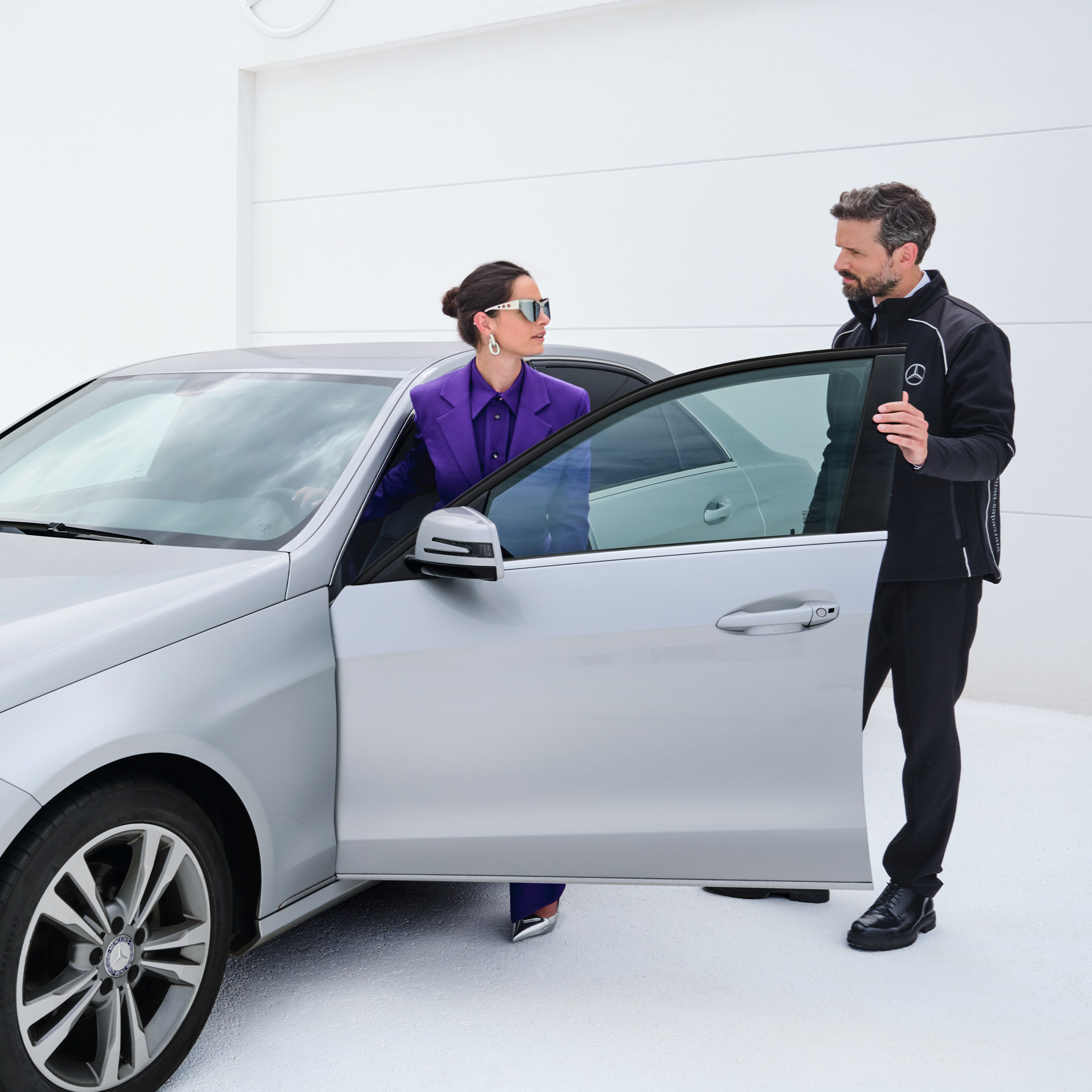 Ophør af serviceapp | Serviceapp | Mercedes-Benz Kvinde stiger ind i sin bil mens hun taler med Mercedes-Benz servicemedarbejder