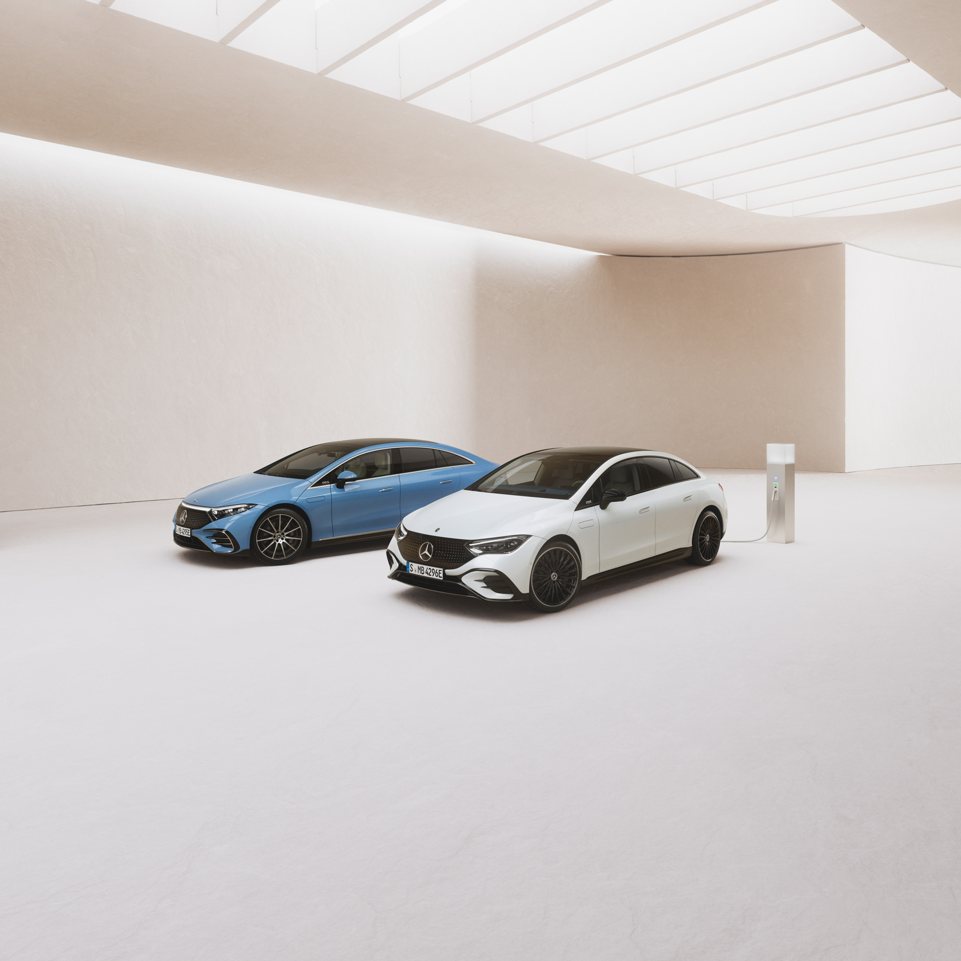 Erhvervsleasing af Mercedes-Benz elbil | Mercedes-Benz Finans To elektriske Mercedes-Benz biler ved siden af en ladestander i et showroom.