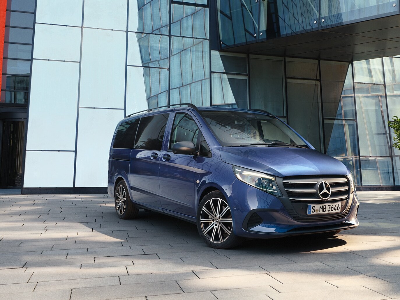 Mercedes‑Benz Vito Tourer med skydedør foran en moderne bygning.