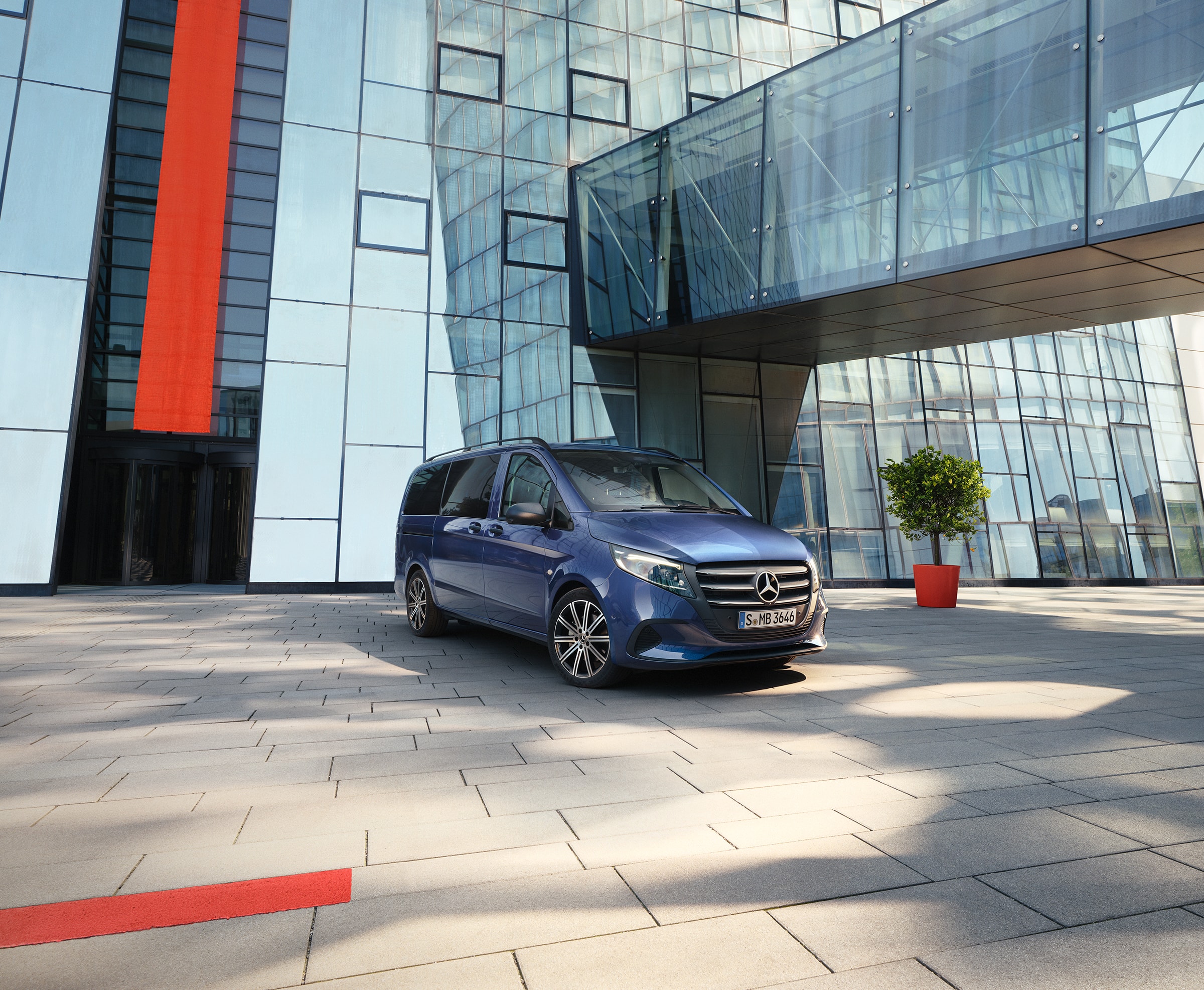 Store familiebiler | Vito Tourer | Mercedes-Benz MPV Mercedes‑Benz Vito Tourer med skydedør foran en moderne bygning.