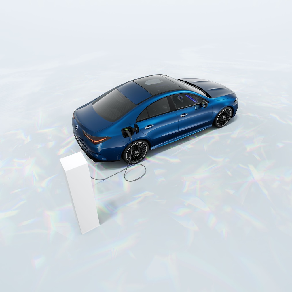 En Mercedes-Benz CLA 250 e coupé med EQ-hybridteknologi, der står ved en ladestation.