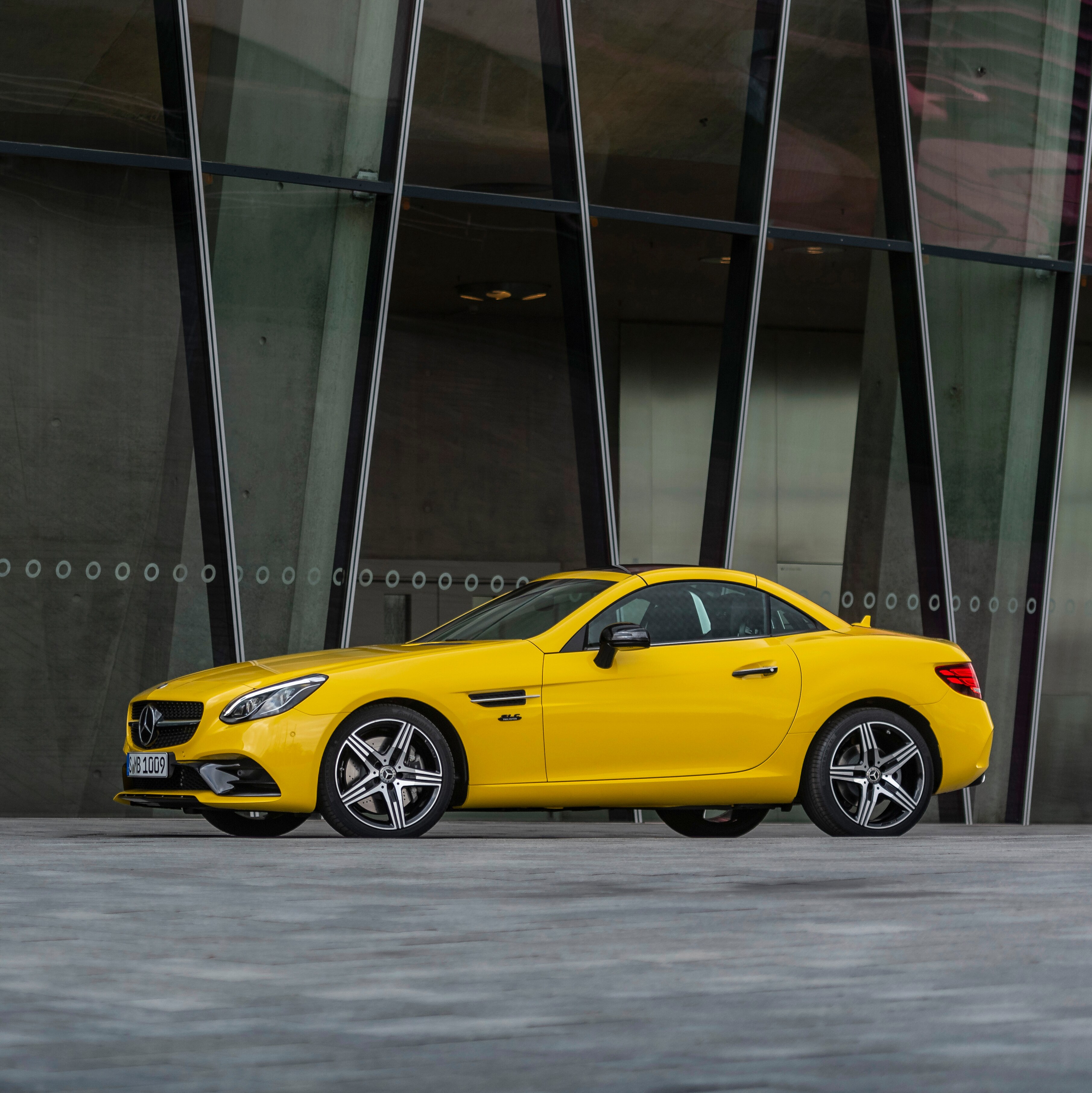 Gul Mercedes-Benz SLC final edition parkeret foran en stor bygning.
