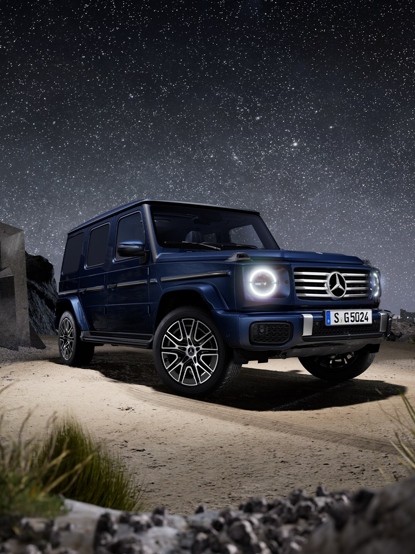 Mørkeblå Mercedes-Benz G-Klasse set skråt forfra med stjerneklar nattehimmel