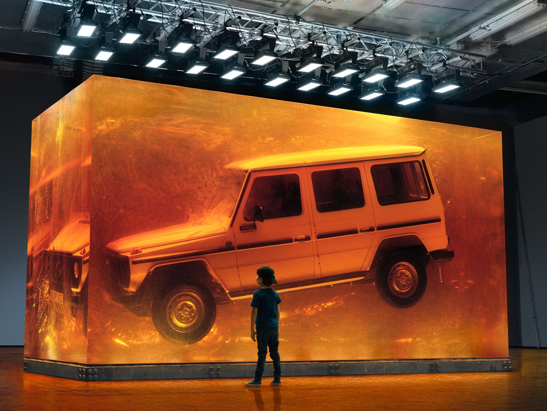 Dreng ser på svævende Mercedes-Benz G-Klasse udstillet i glas.