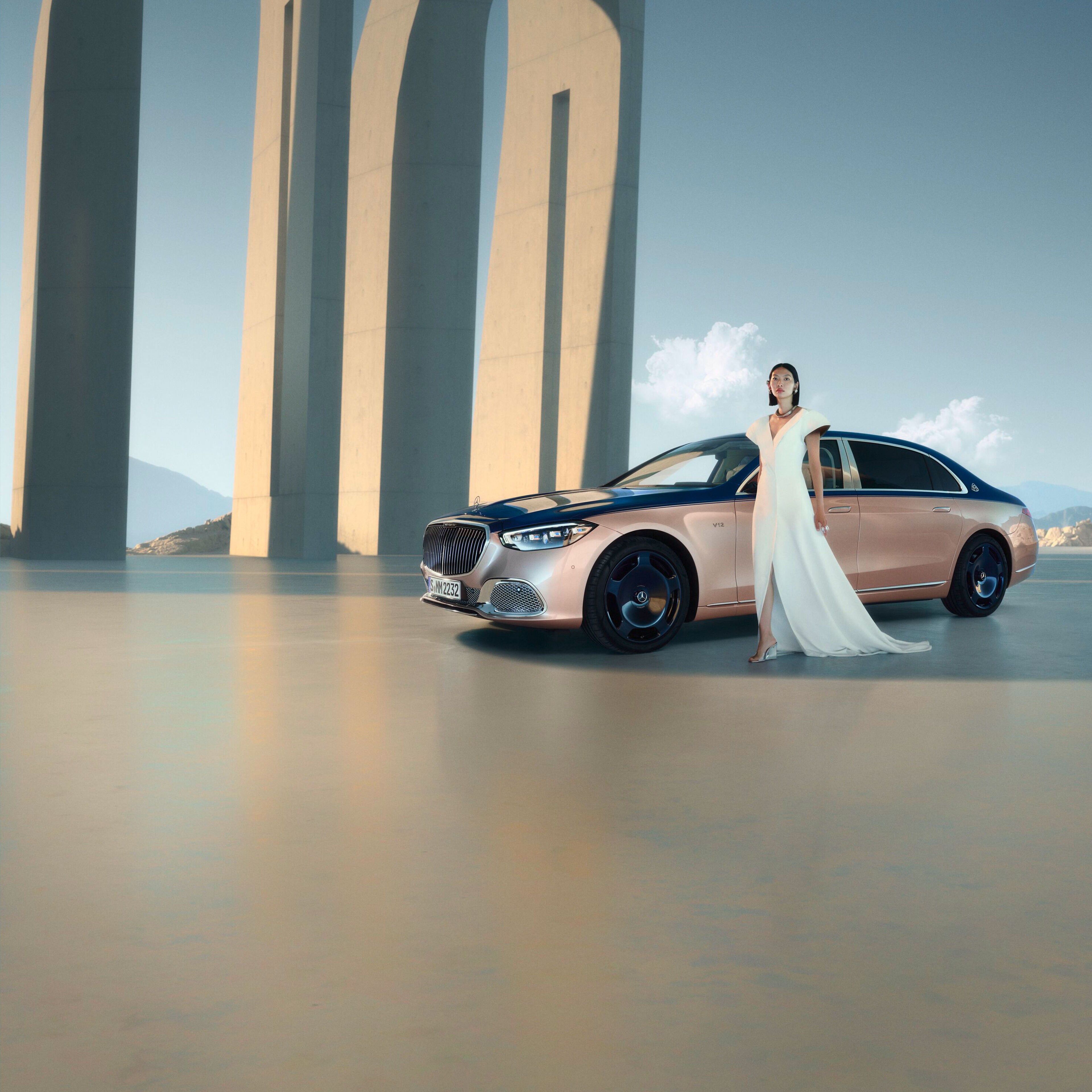 Kvinde i hvid kjole foran Mercedes-Maybach i tofarvet lakering