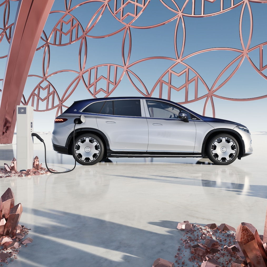 Mercedes-Maybach EQS SUV'en set fra siden ved ladestationen med Maybach mærkelogoet i baggrunden.