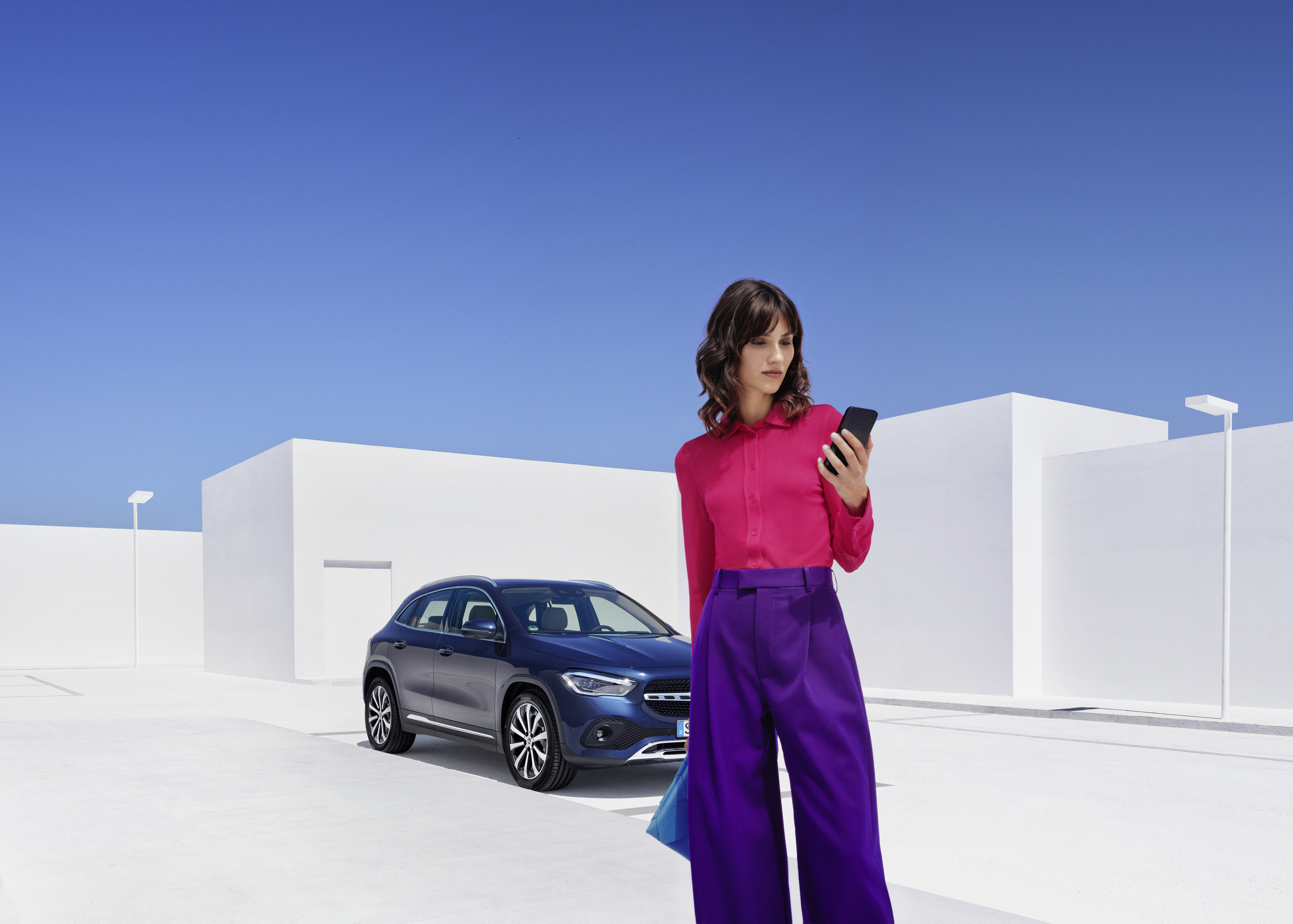 Vejhjælp | Mercedes-Benz Kvinde står foran sin Mercedes-Benz og kigger på sin smartphone