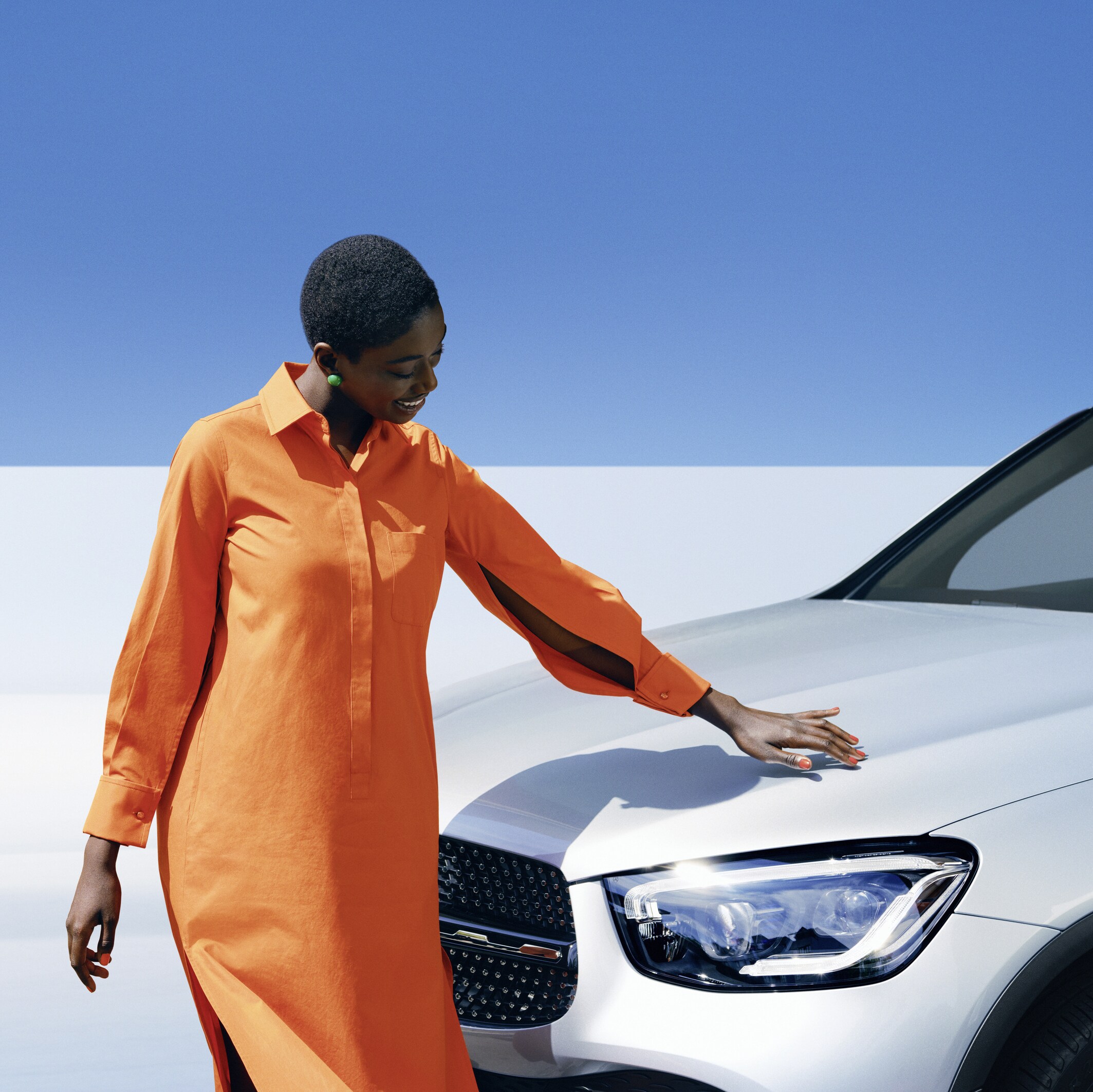 Kvinde beundrer den skinnende lak på sin hvide Mercedes-Benz personbil i dagslys
