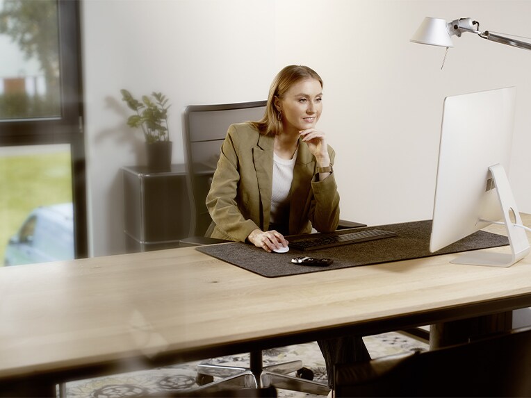 Kvinde arbejder på sin computer ved kontorplads