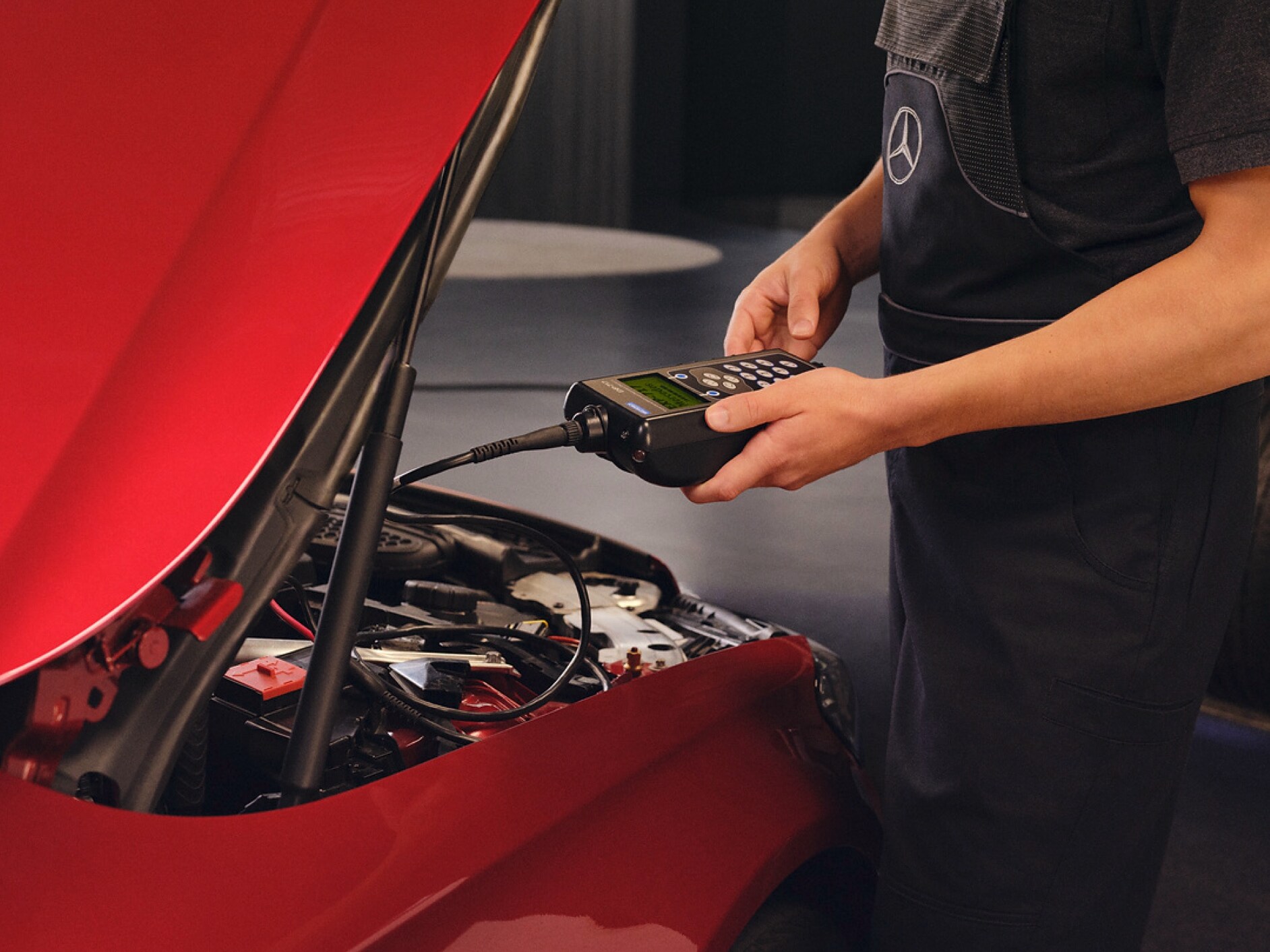 Mercedes-Benz tekniker udfører serviceeftersyn af rød Mercedes-Benz