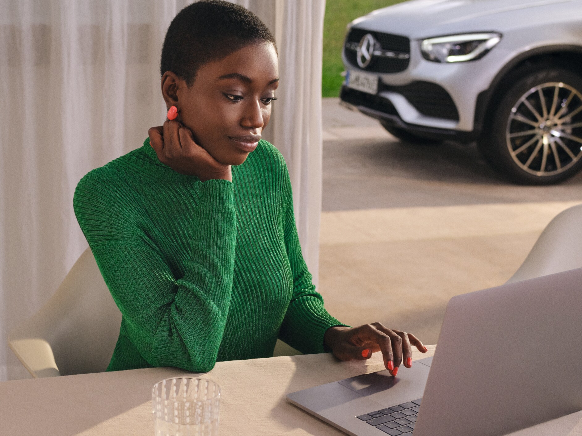 Kvinde bruger computer. Mercedes-Benz parkeret i indkørsel bagved