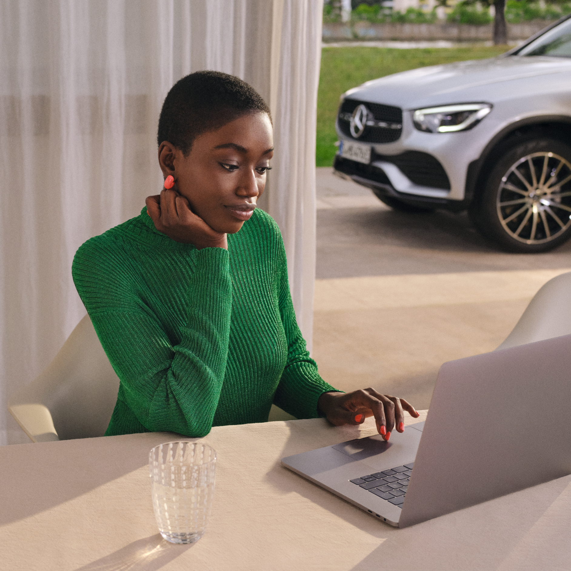 Hovedkontor | Kundeservice | Mercedes-Benz Kvinde bruger computer. Mercedes-Benz parkeret i indkørsel bagved