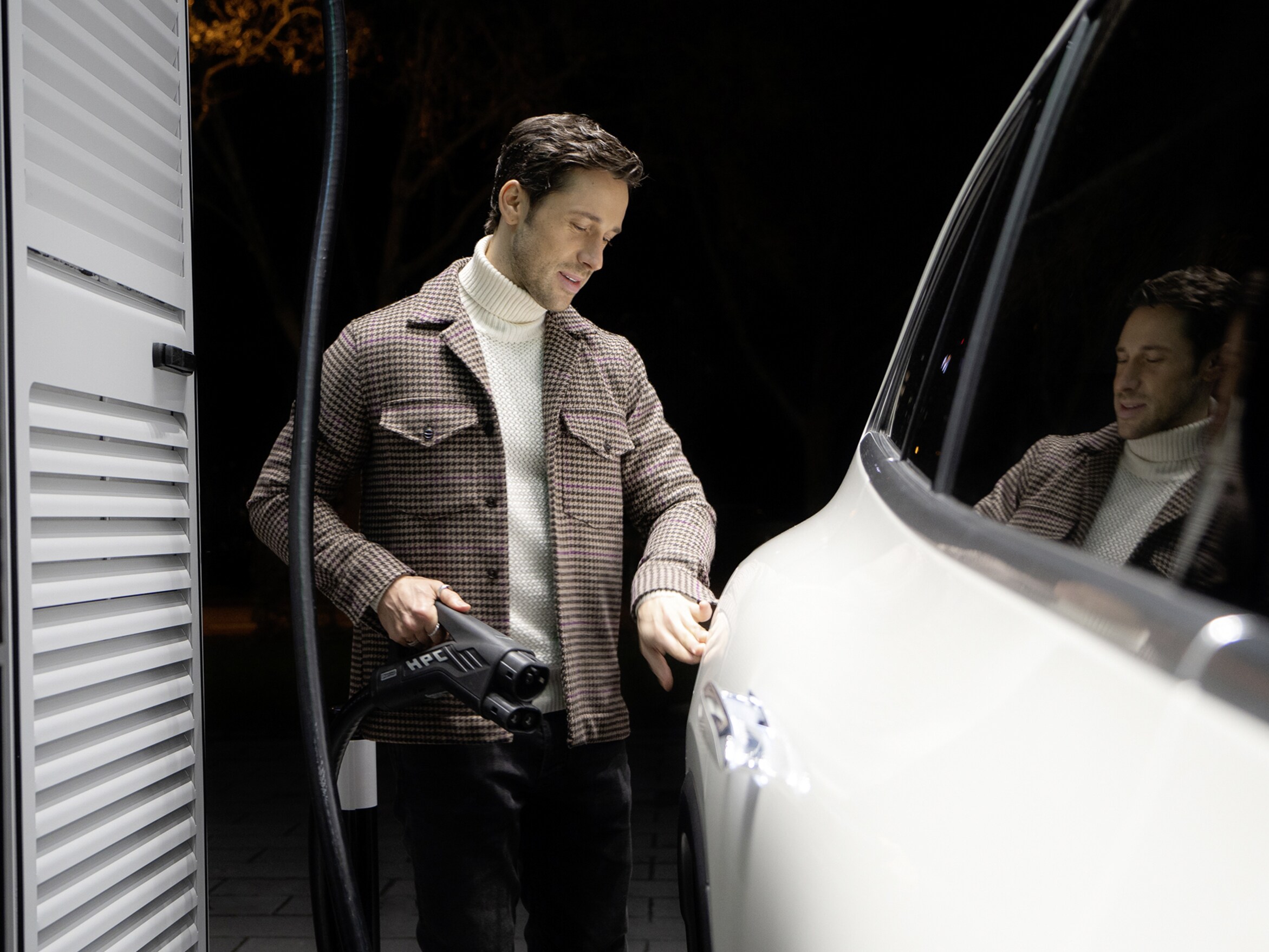 Mand står med ladekabel i hånden ved siden af sin elektriske Mercedes-Benz