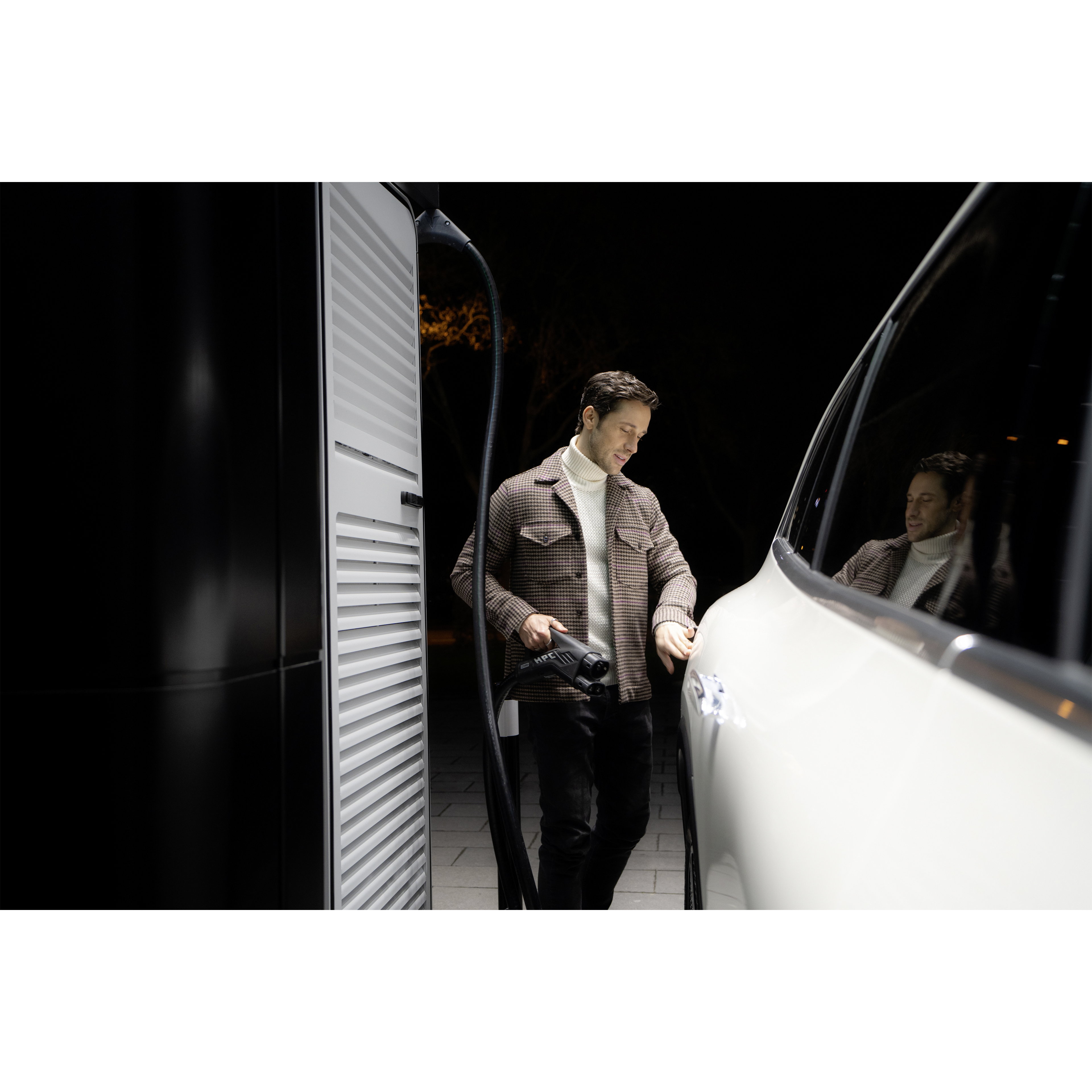 Ladeløsninger | Mercedes-Benz Mand oplader sin elektriske Mercedes-Benz bil ved en ladestander