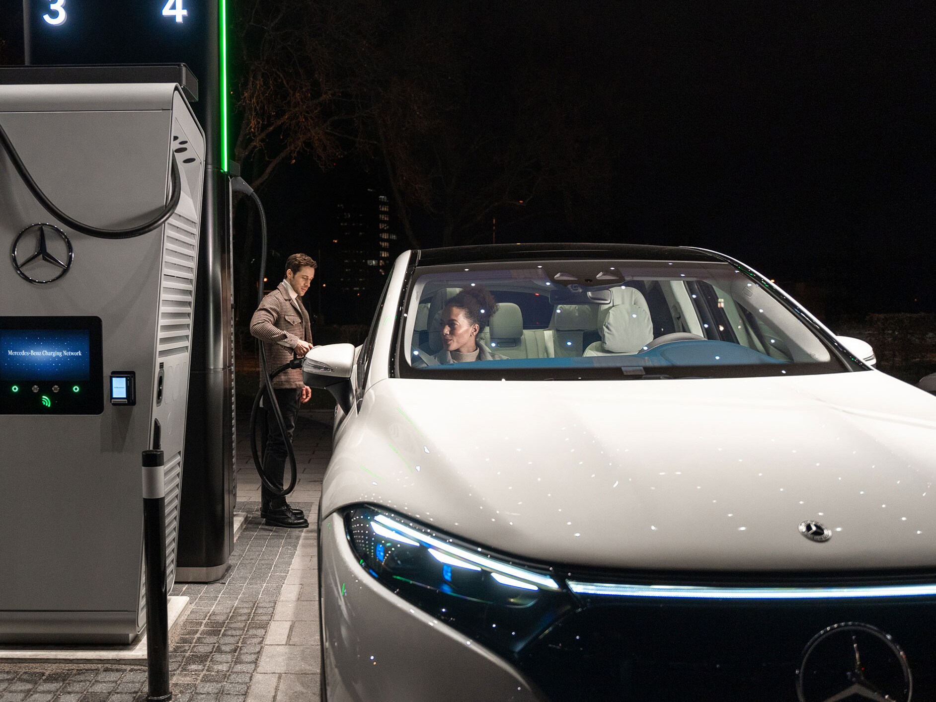 Mercedes-Benz CLA holder på en gade og er tilsluttet en ladestation.