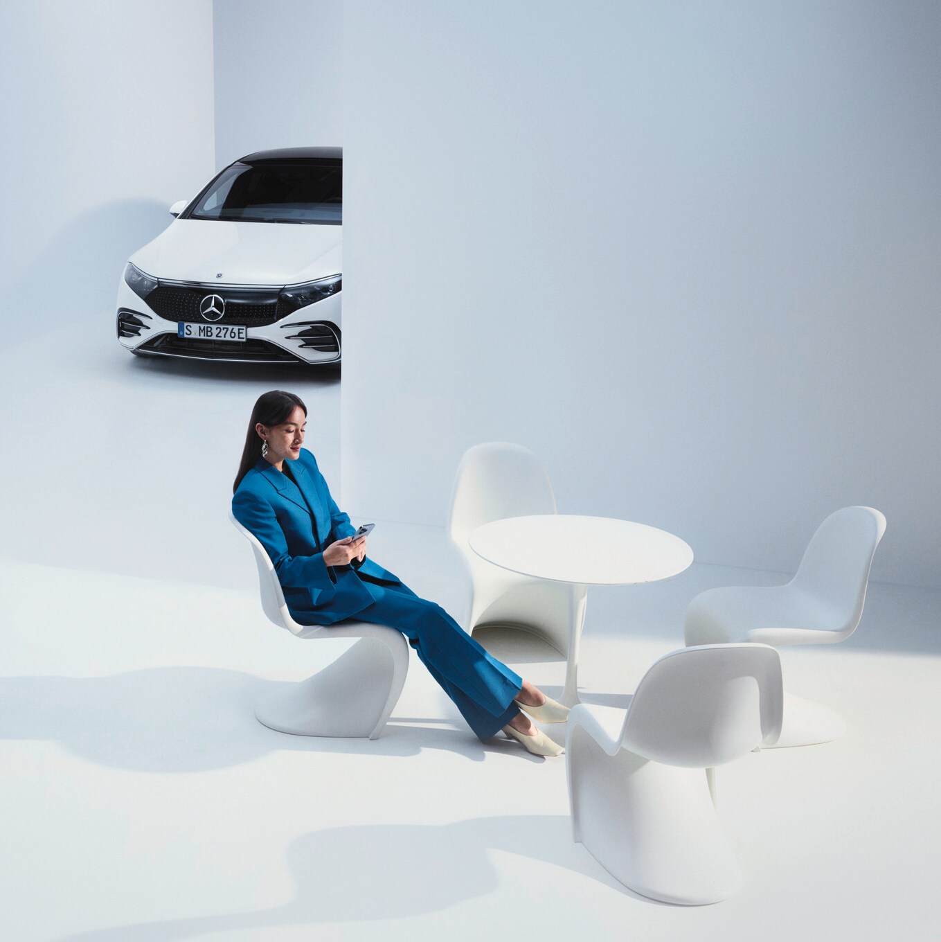 Kvinde sidder i et futuristisk miljø med en Mercedes-Benz i baggrunden