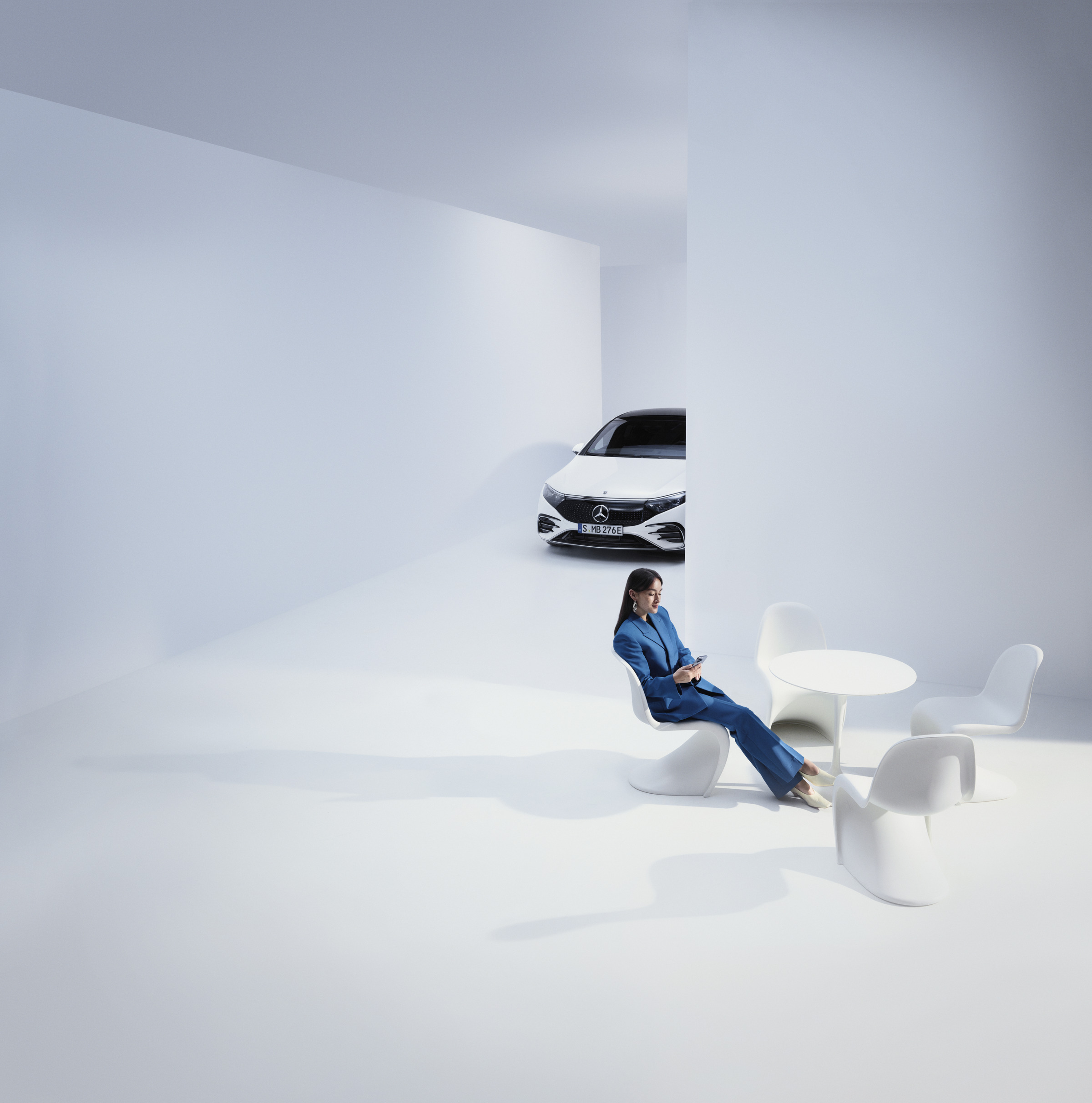 Klage og klagehåndtering | Mercedes-Benz Kvinde sidder i et futuristisk miljø med en Mercedes-Benz i baggrunden