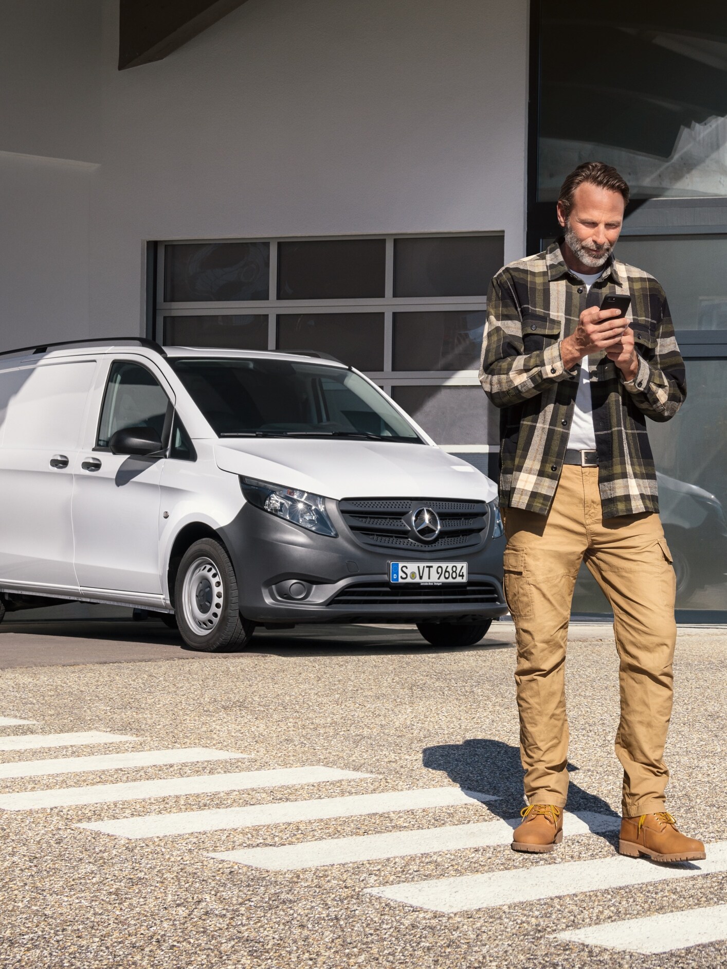 Mand foran Mercedes-Benz varebil betjener sin mobiltelefon