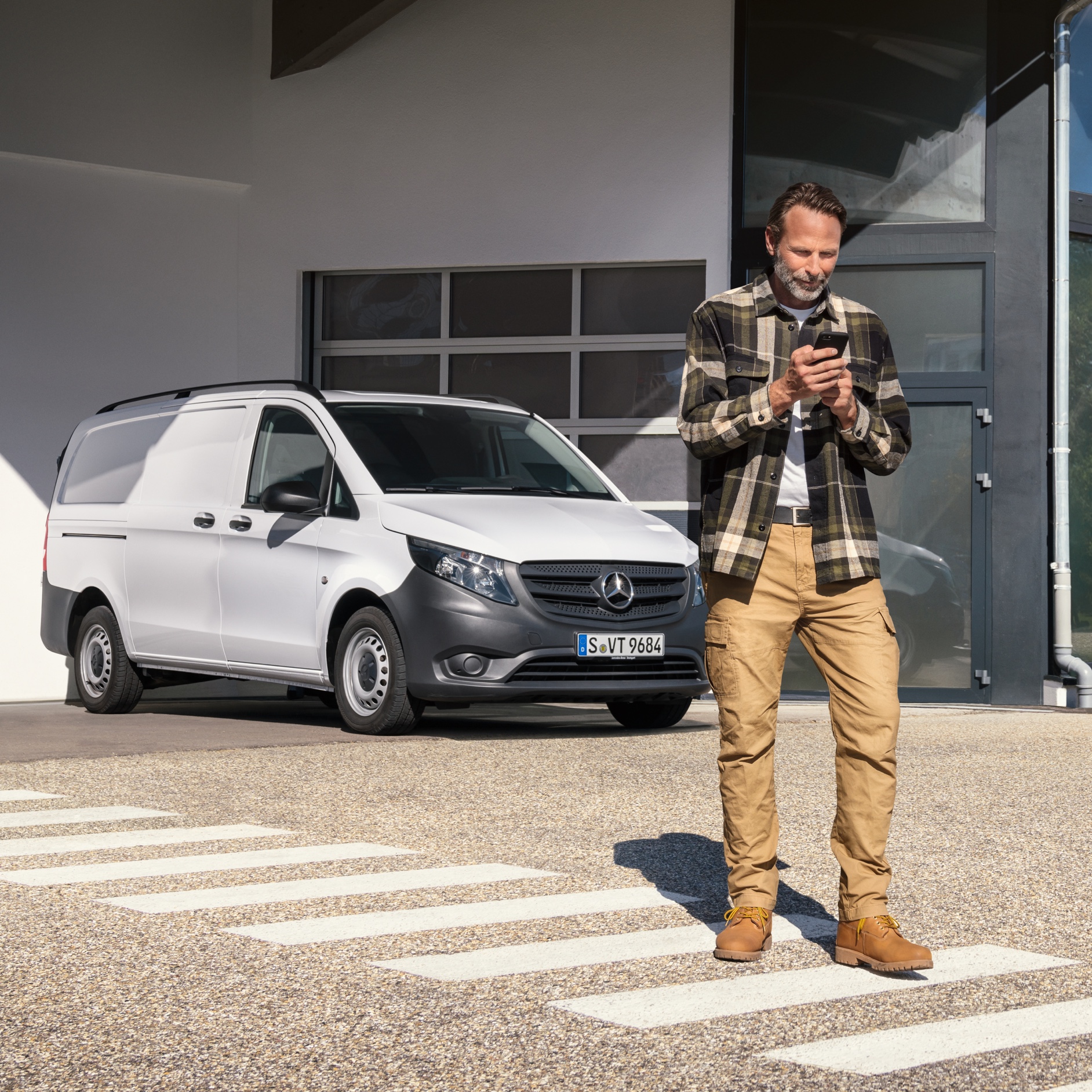 Kundeservice | Mercedes-Benz Vans Mand foran Mercedes-Benz varebil betjener sin mobiltelefon