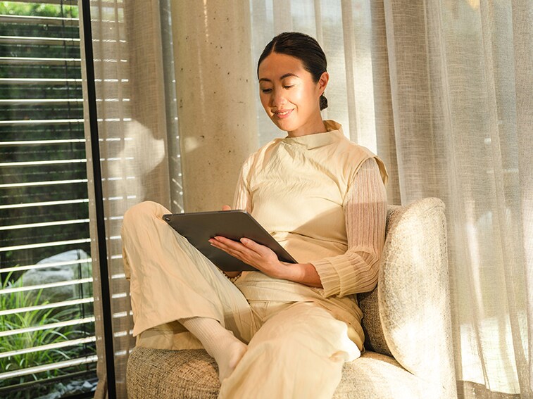 Kvinde sidder afslappet i stil og bruger sin tablet