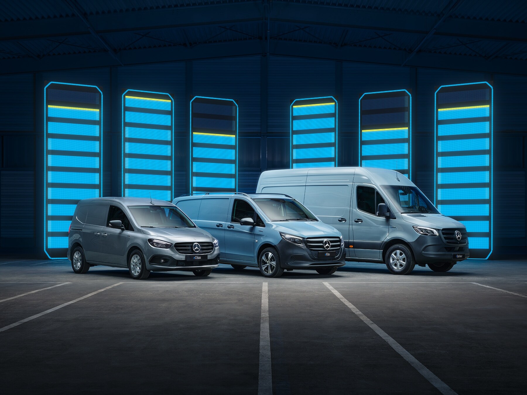 En række Mercedes-Benz elektriske varebiler udstillet i en futuristisk lagerhal