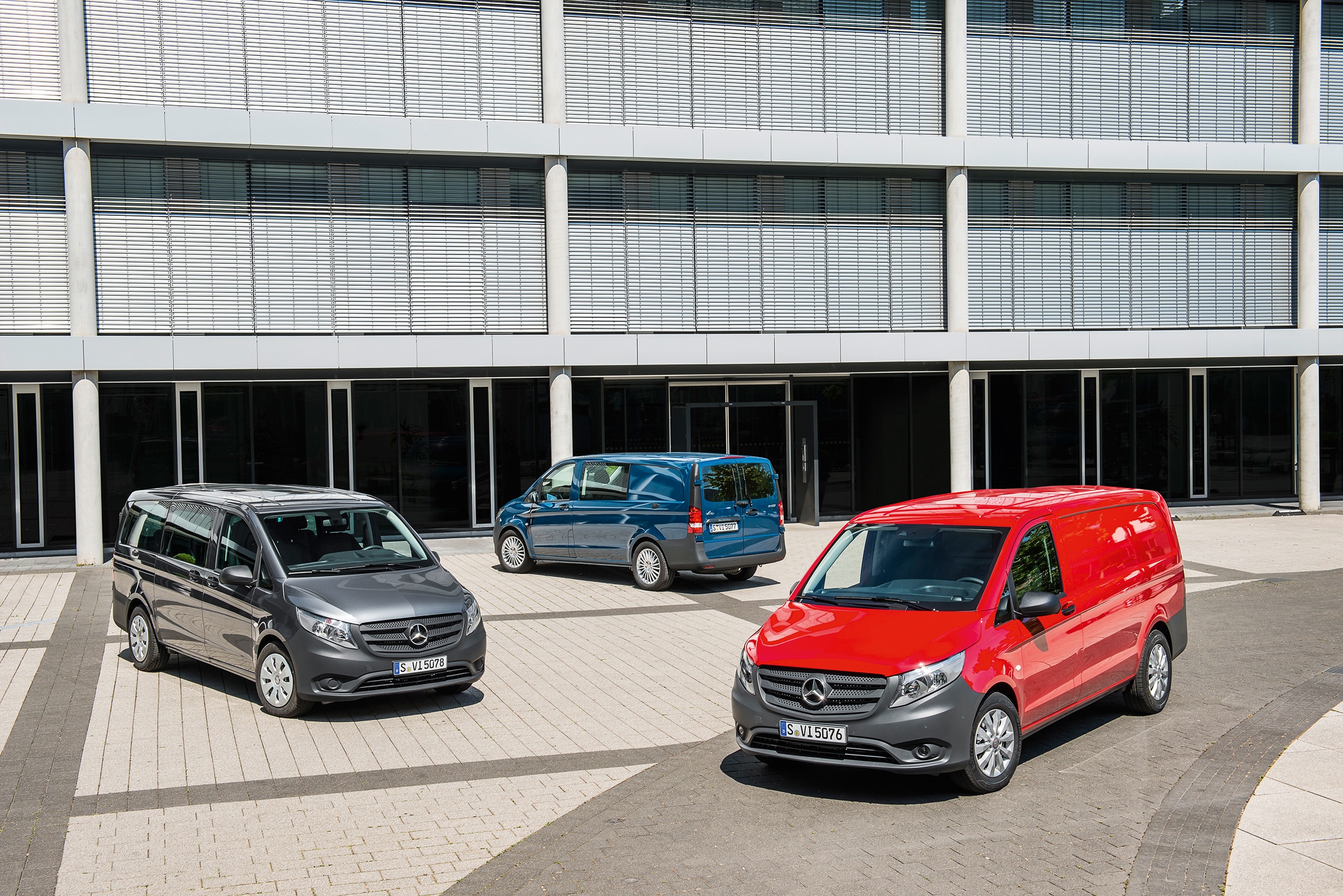 Tredje generation af Vito | Historien bag erhvervskøretøjerne | Mercedes-Benz Tre Mercedes-Benz Vito parkeret foran en moderne kontorbygning