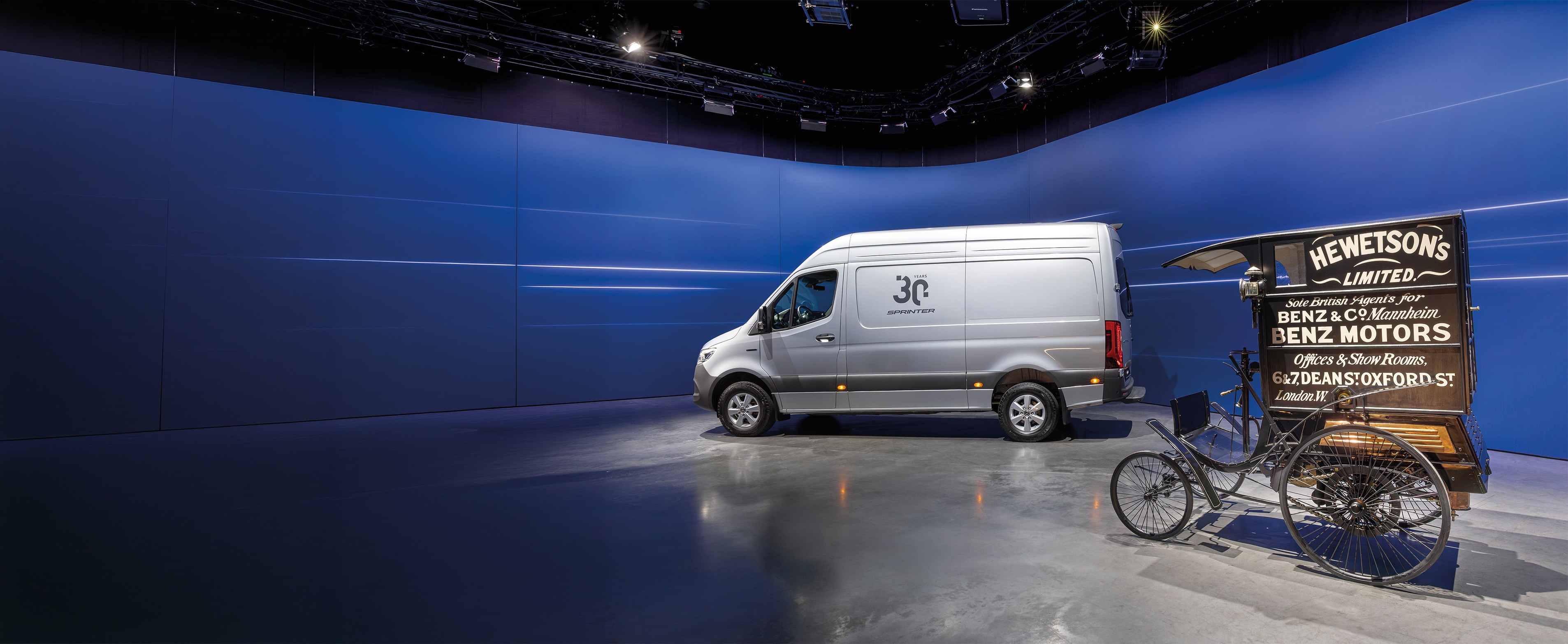 Historie | Erhvervskøretøjer | Mercedes-Benz Sprinter kassevogn og historisk Benz-varevogn udstillet i et moderne showroom