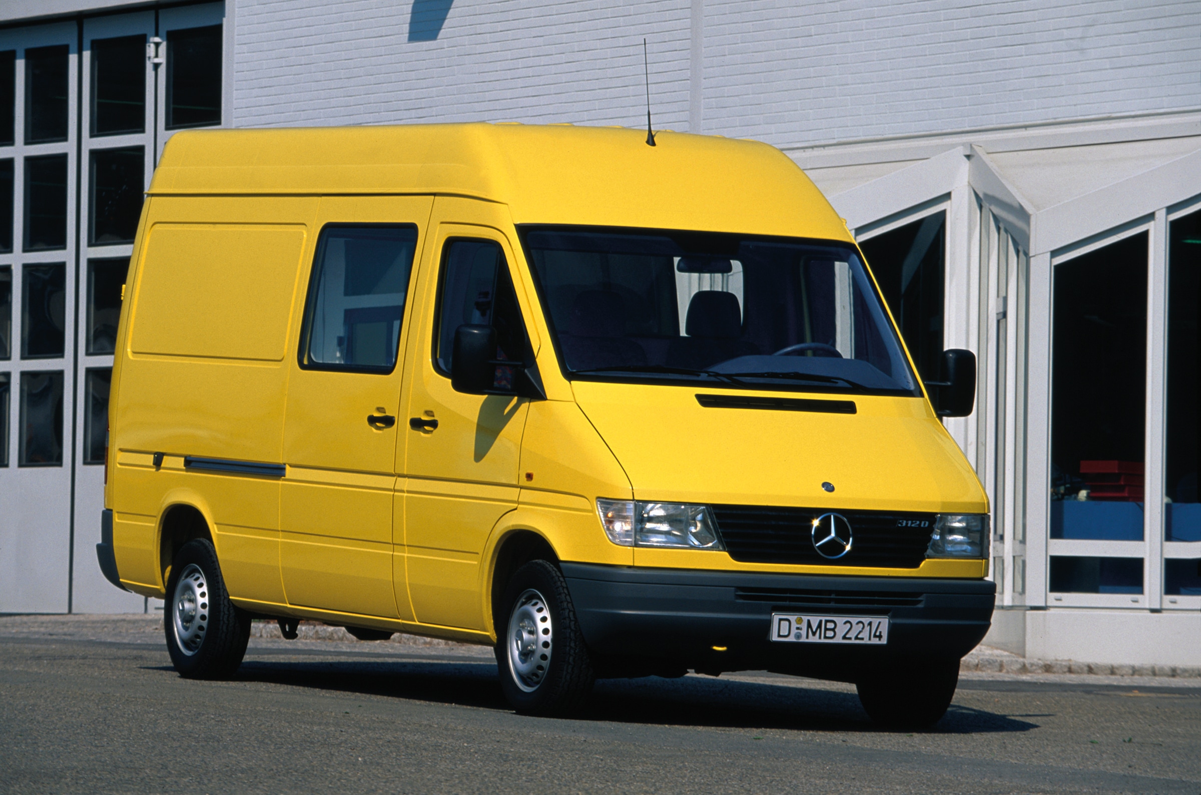 Den første generation af Mercedes-Benz Sprintere | Historien bag erhvervskøretøjerne | Mercedes-Benz Først generations Sprinter parkeret uden for en industribygning