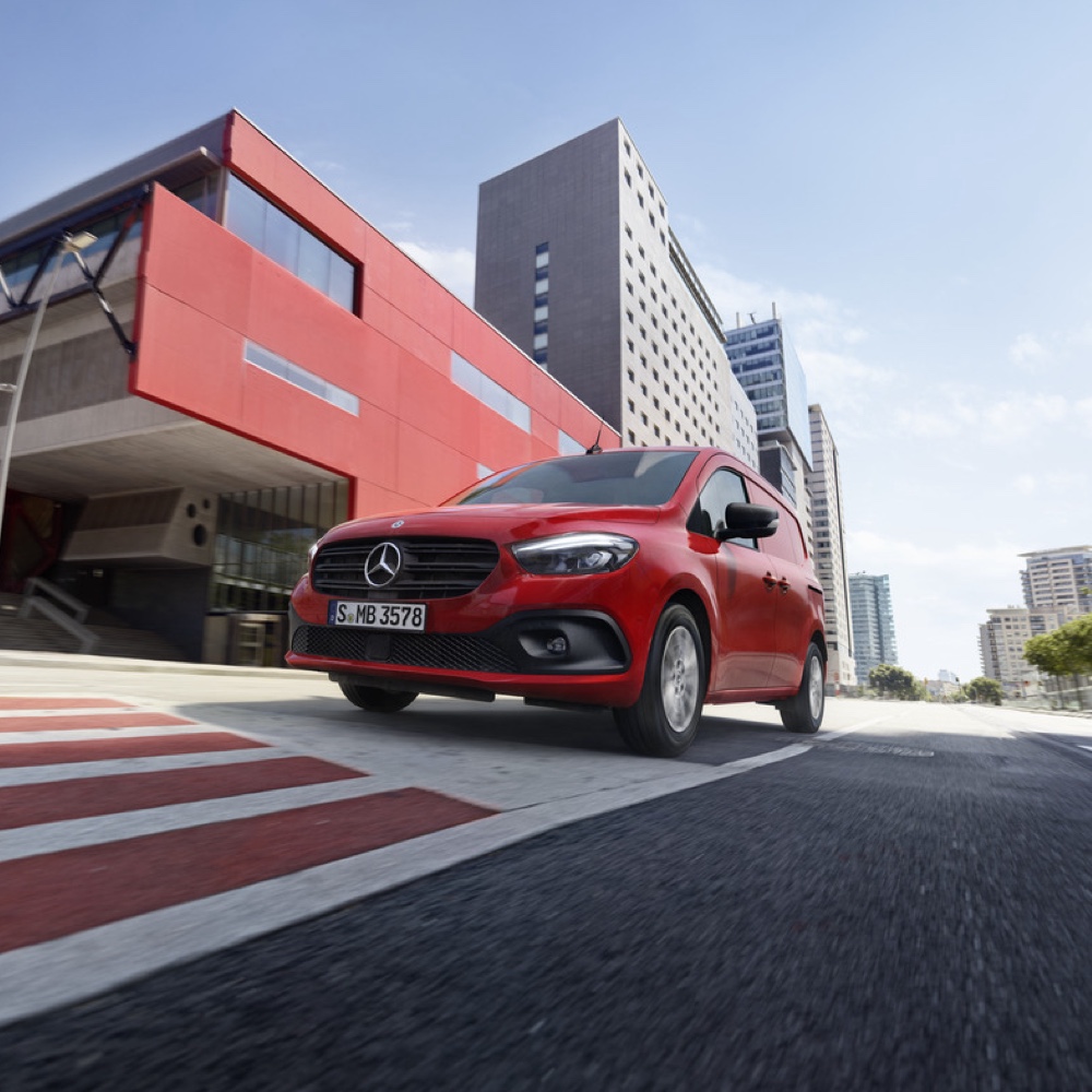 Citan og eCitan | Mercedes-Benz En rød Mercedes-Benz Citan varevogn kører gennem en storby.